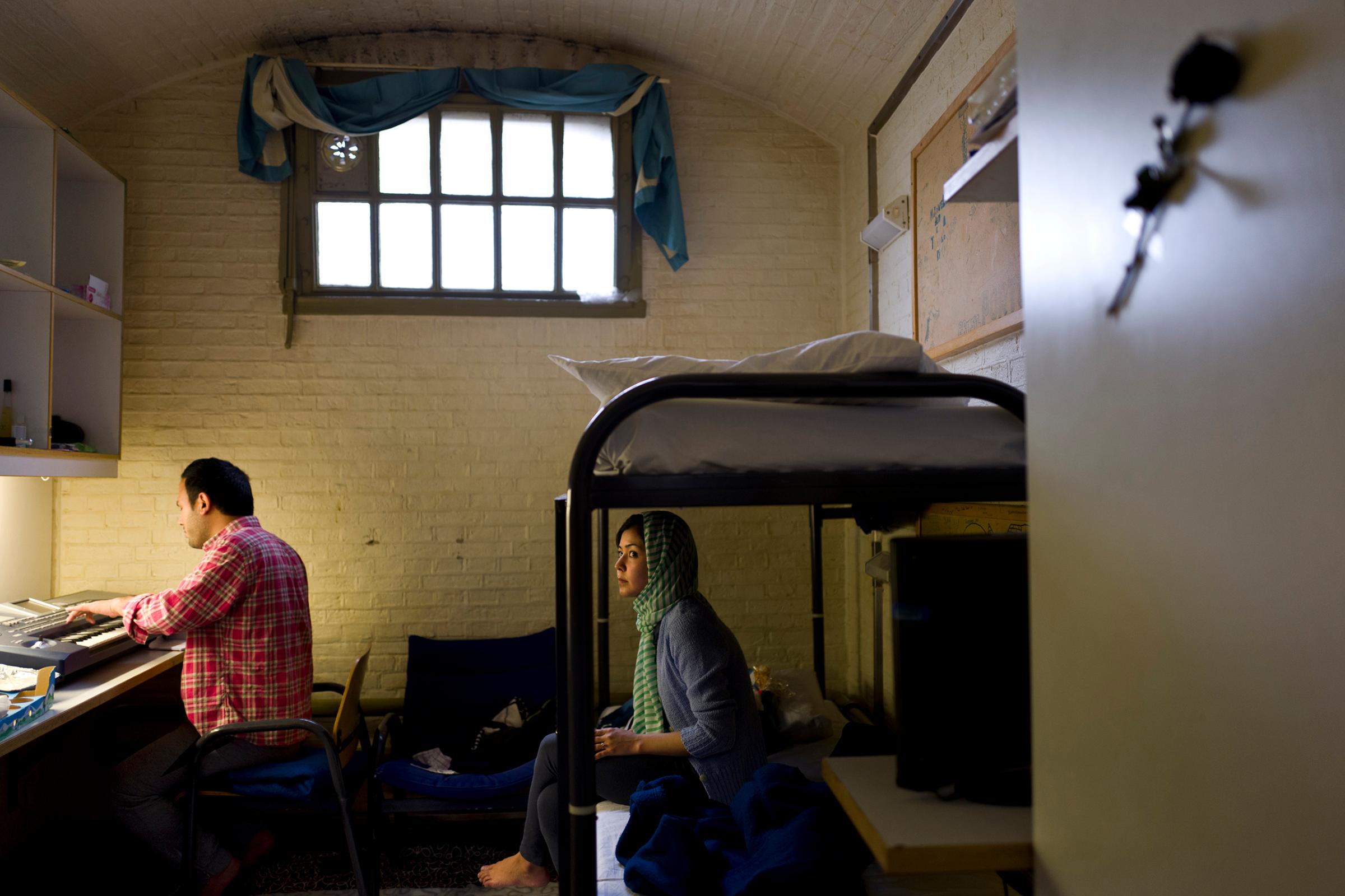 Afghan refugee Hamed Karmi, 27, plays keyboard next to his wife Farishta Morahami, 25, sitting on a bed inside their room at the former prison of De Koepel in Haarlem, Netherlands, April 6, 2016.