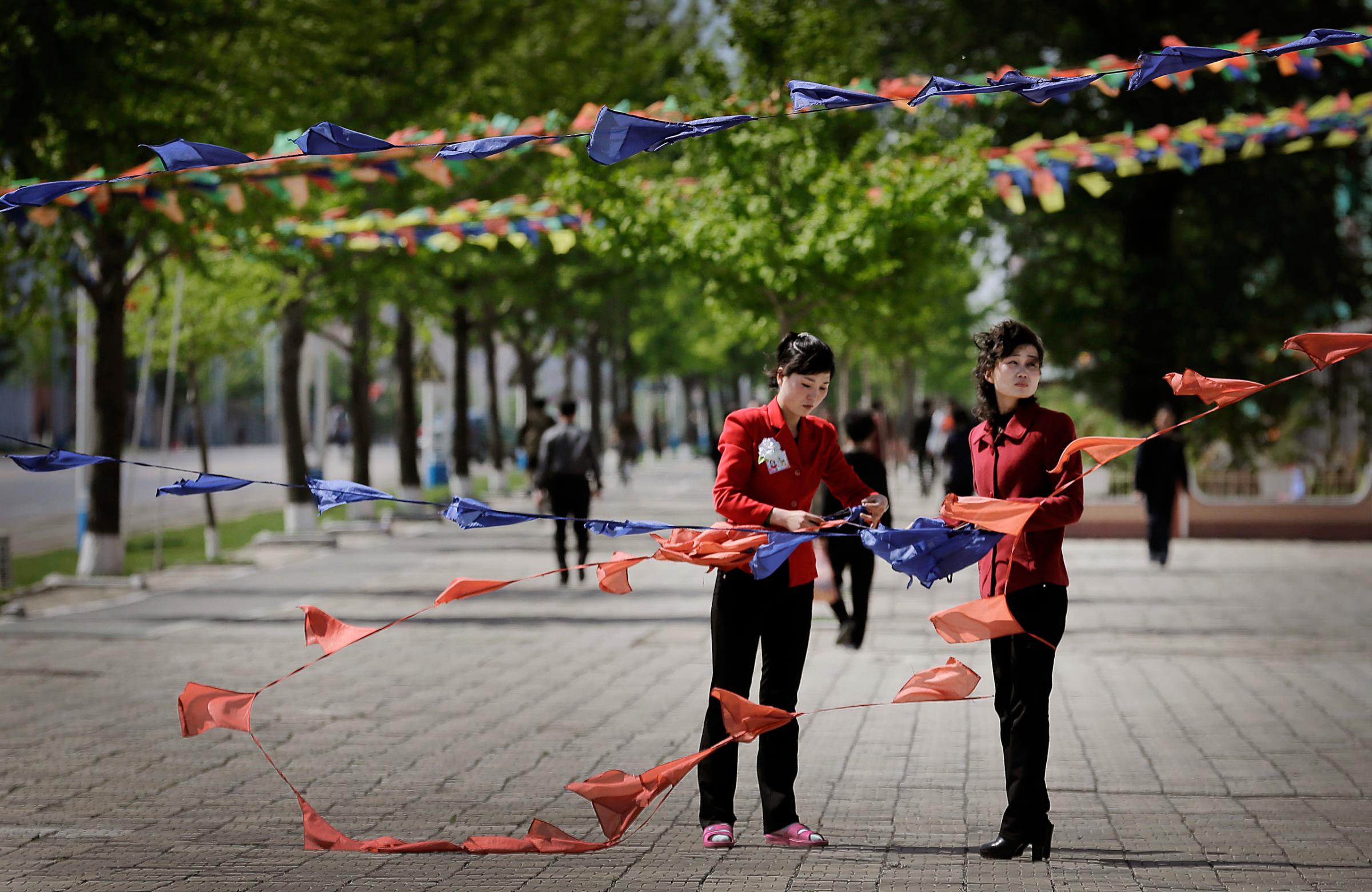 North Korean women tie flags as they decorate the streets in downtown Pyongyang, North Korea Saturday, May 7, 2016. North Korean leader Kim Jong Un hailed his country's recent nuclear test to uproarious applause as he convened the first full congress of its ruling party since 1980, an event intended to showcase the North's stability and unity in the face of tough international sanctions and deepening isolation. (AP Photo/Wong Maye-E)