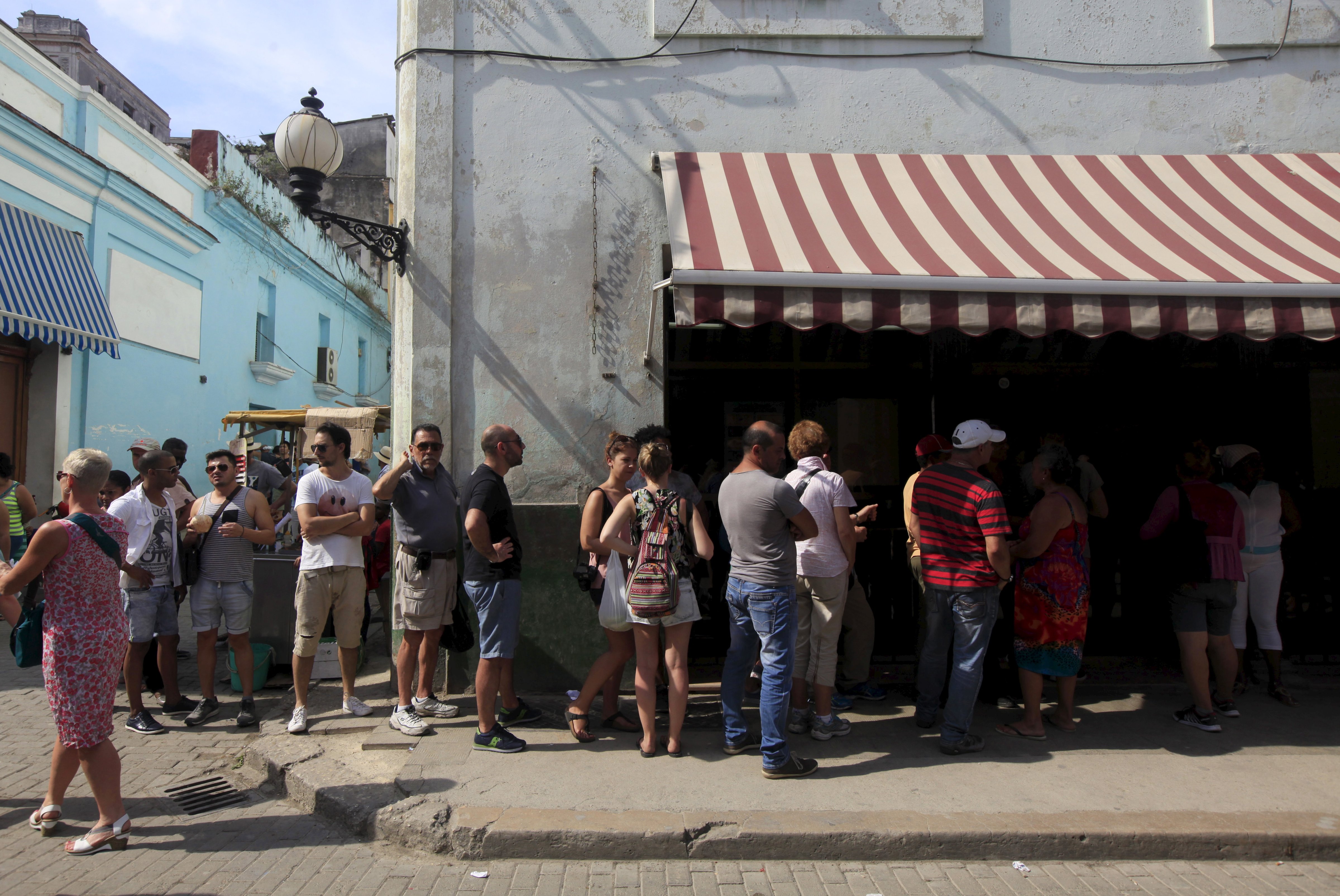People stand outside a currency exchange shop to change money in Havana