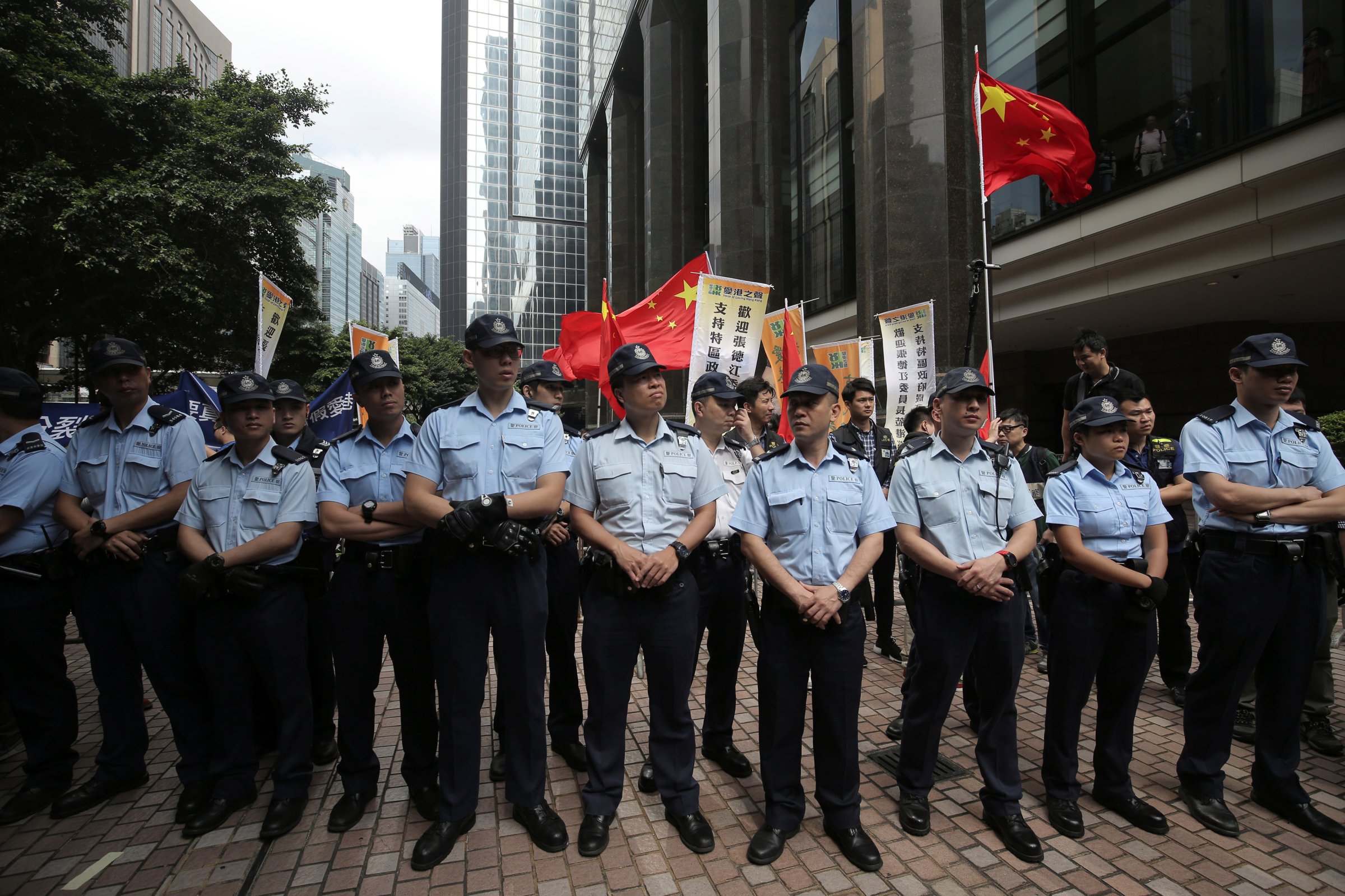 Police officers patrol in front of supporters of visiting Zhang Dejiang, the chairman of China's National People's Congress, during a protest against him in Hong Kong