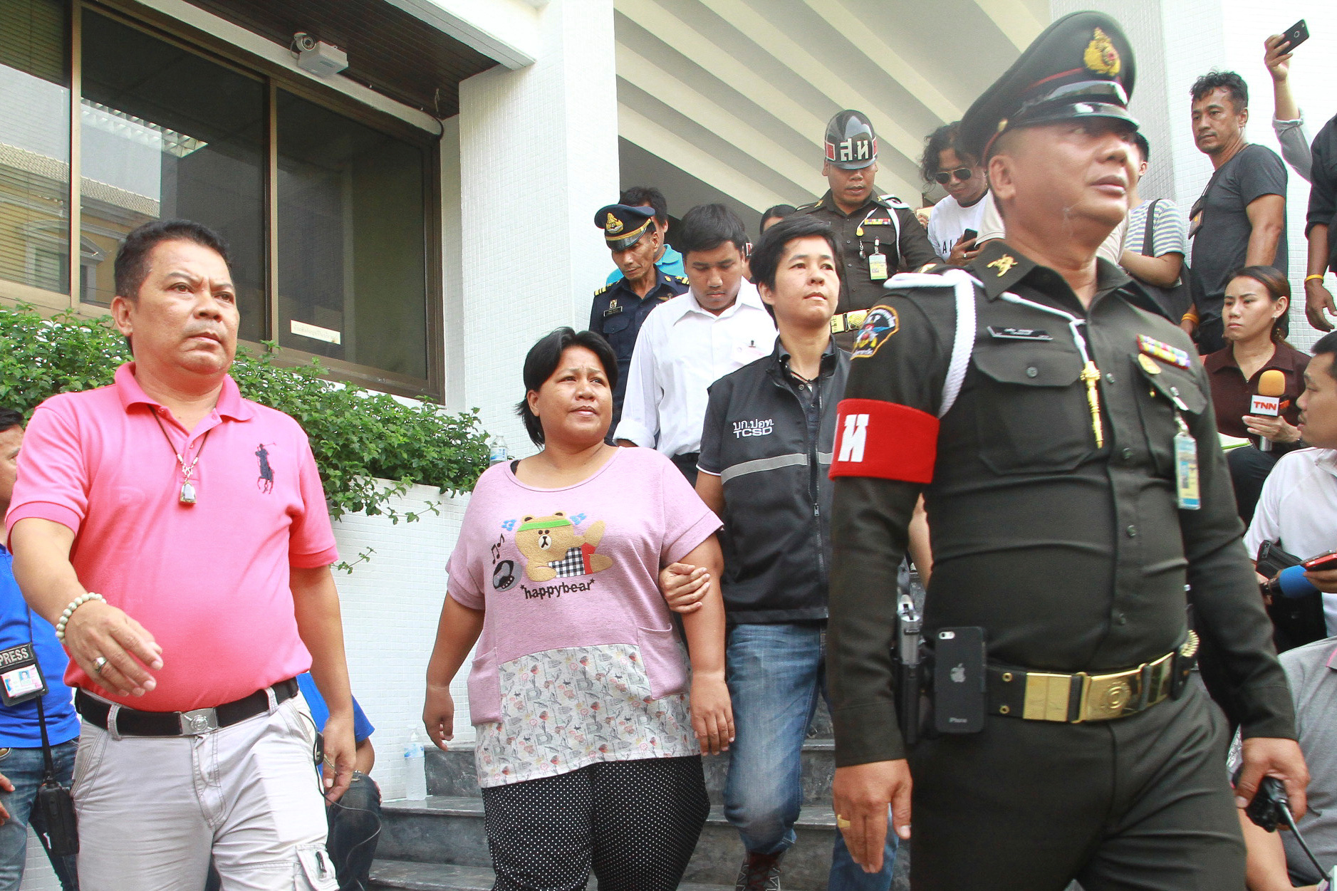 Patnaree Chankij, the mother of an anti-junta activist, is escorted by police as she leaves a military court in Bangkok