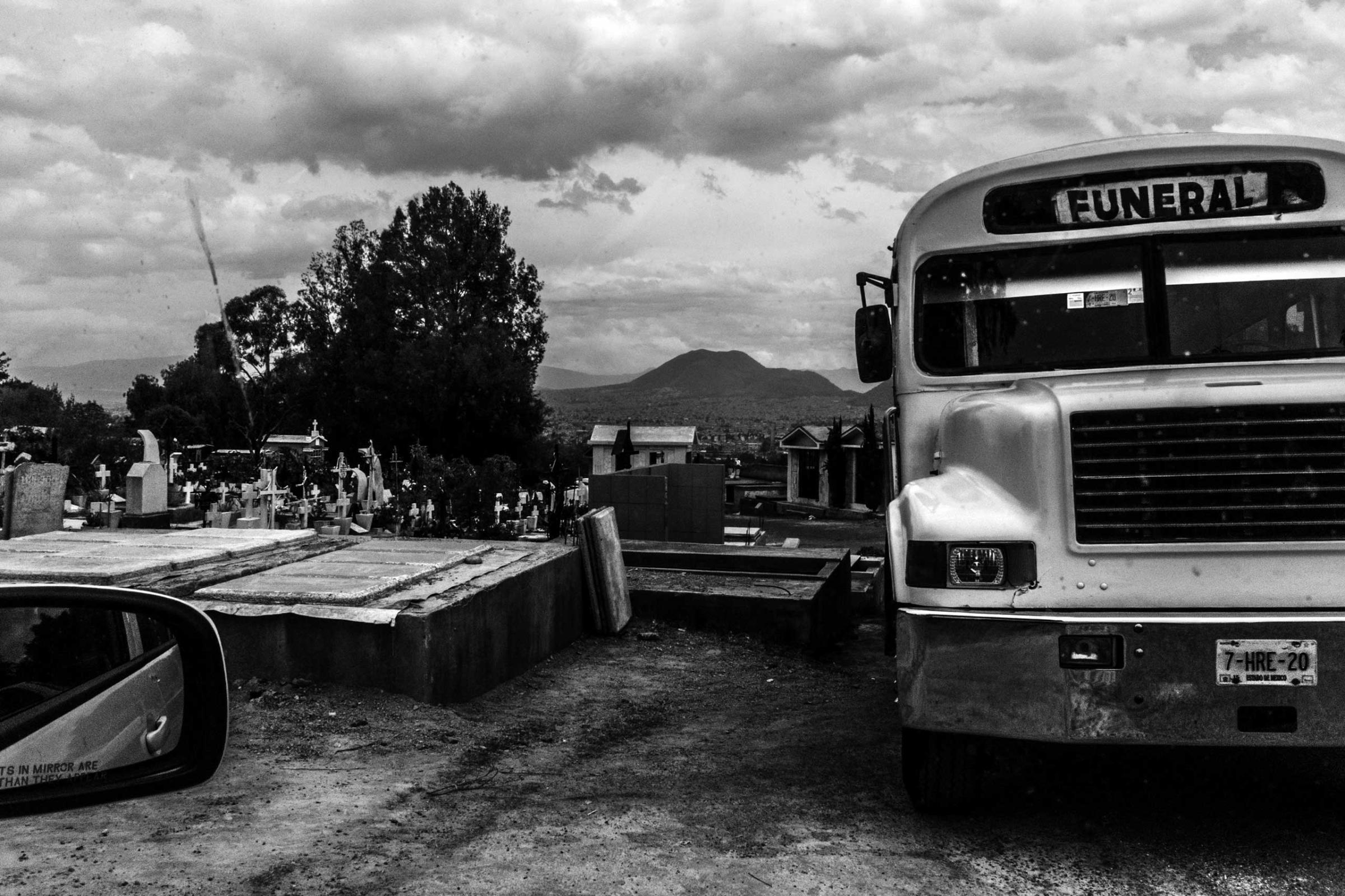 A funeral bus is seeng at the San Nicolas Tolentino cementary. For practical reasonsm Families and friends ussualy rent a bus to get to the funerals.