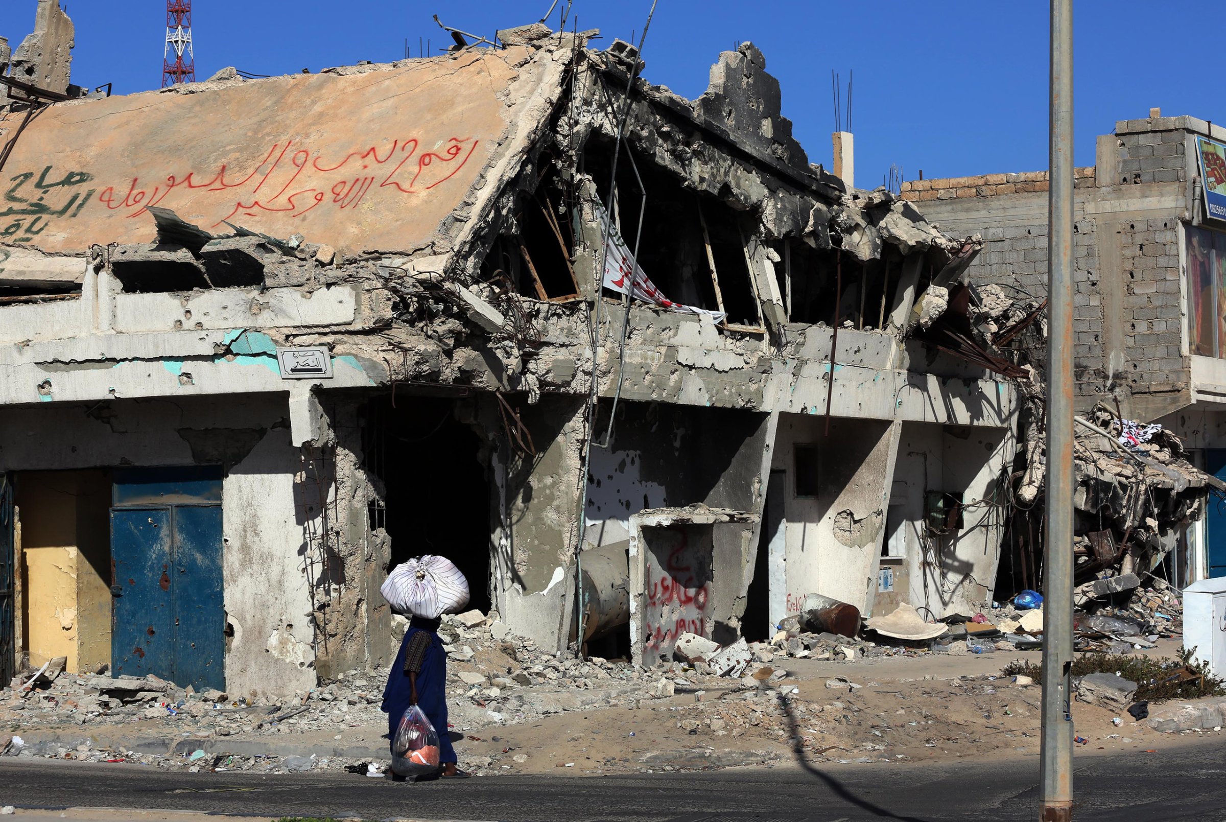 A Libyan woman walks past the rubble of a building in the Mediterranean city of Sirte, Oct. 13, 2012.