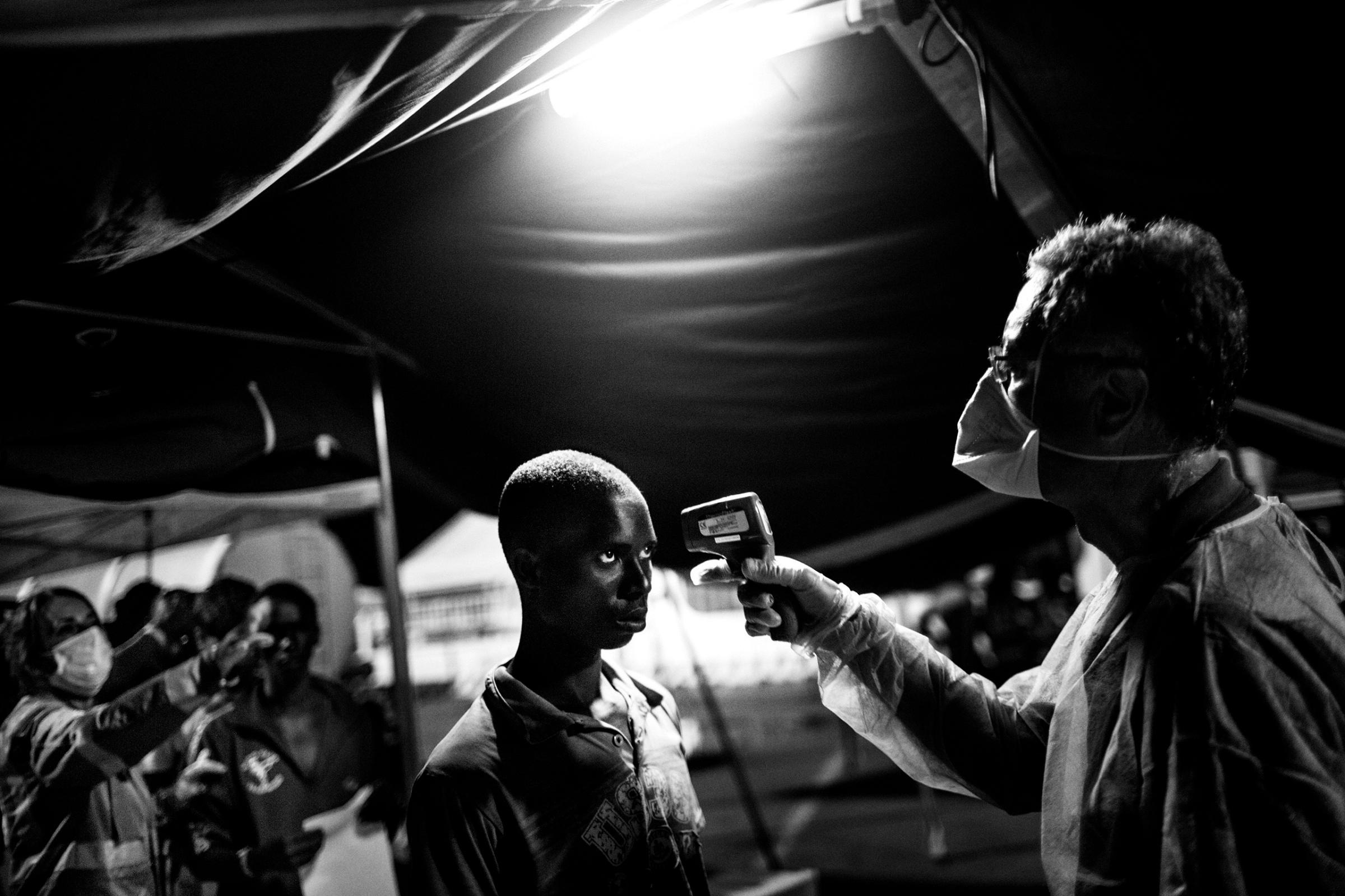 An Italian Red Cross doctor uses an electronic thermometer to take the temperature of a boy during the medical exam at the port of Messina, Italy, July 2015.