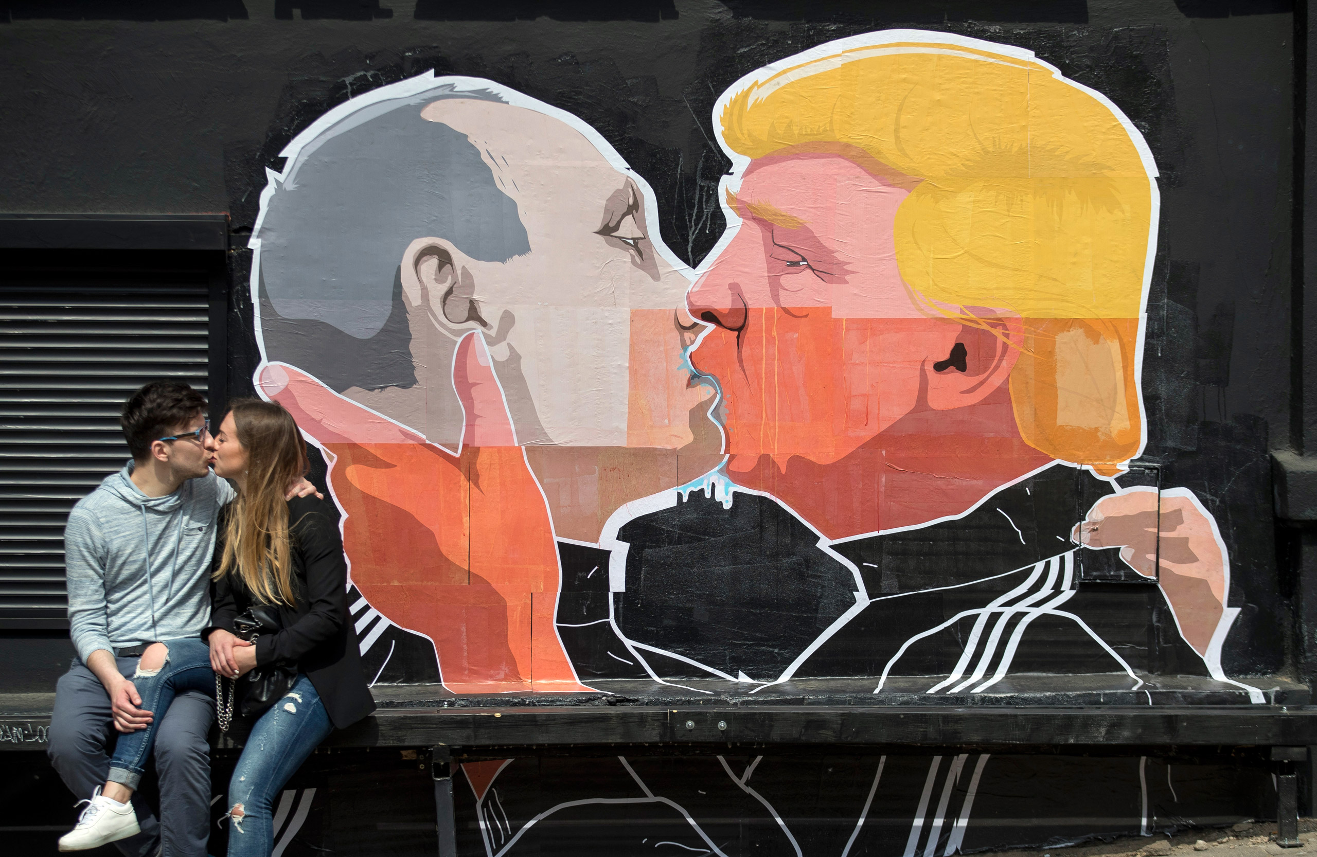 A couple kisses in front of graffiti depicting Russian President Vladimir Putin, left, and Republican presidential candidate Donald Trump, on the walls of a bar in the old town in Vilnius, Lithuania, on May 14, 2016. (Mindaugas Kulbis—AP)