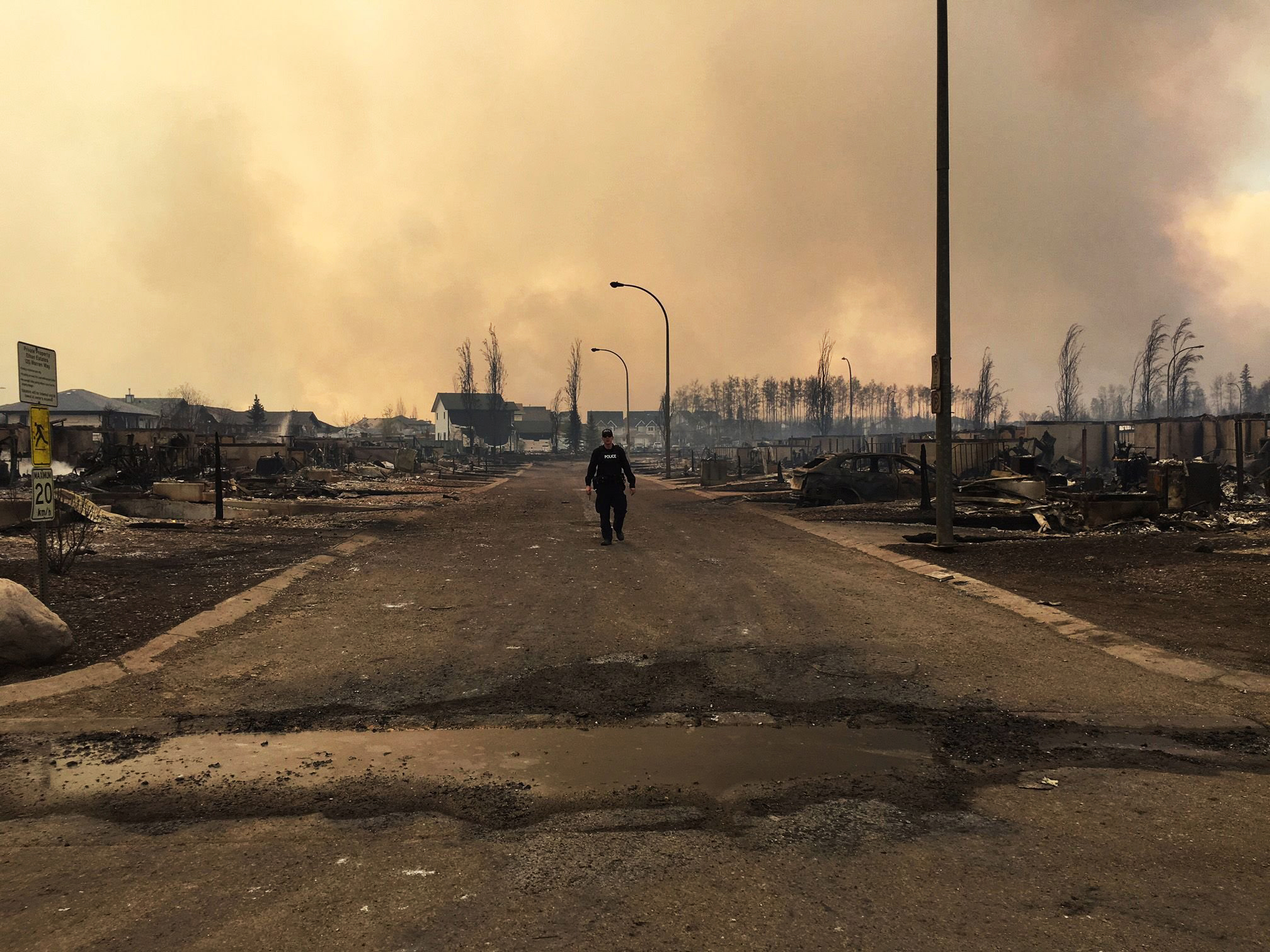 This photo released by the Alberta RCMP on May 5, 2016, shows a police officer walking on a road past burned down houses in Fort McMurray, Alberta. (Albert RCMP/AFP/Getty Images)