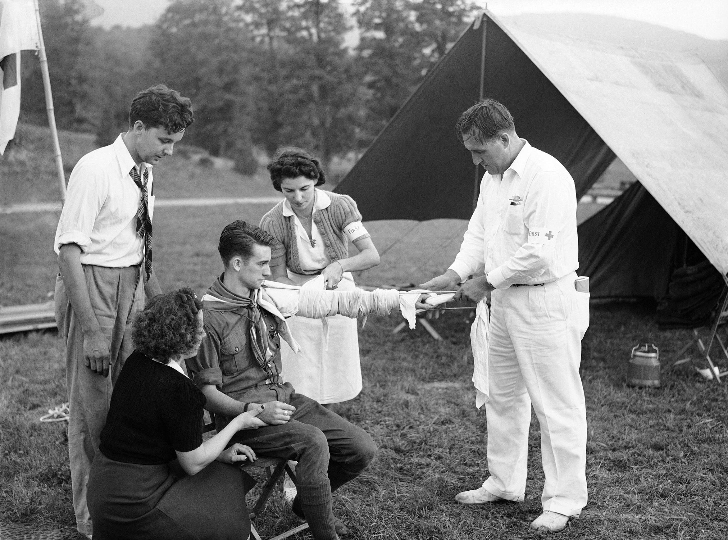A Boy Scout has his arm tied up in a splint after it has been dressed by Red Cross workers from Poughkeepsie, N.Y., following the "evacuation" of about 2,000 New Yorkers who left for Dutchess County in New York, Sept. 9, 1941. Simulating wartime conditions volunteers left the city and drove north to avoid an imaginary "bombing" of New York. It was part of a demonstration of civilian defense work.