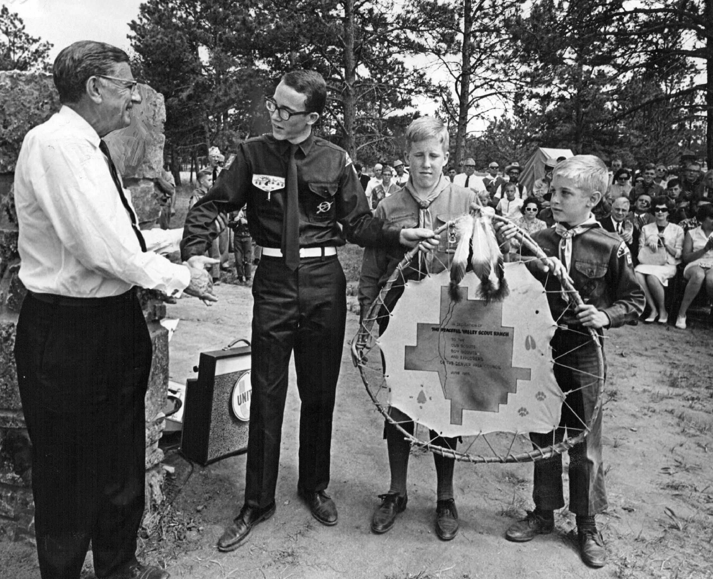 J. Clinton Bowman, president of the Denver Area Council, Boy Scouts of America, presents a leather map of the Peaceful Valley Scout Ranch to three representatives of the Scouts- from left, Keat, Phil and Roger Johnson. 1966.
