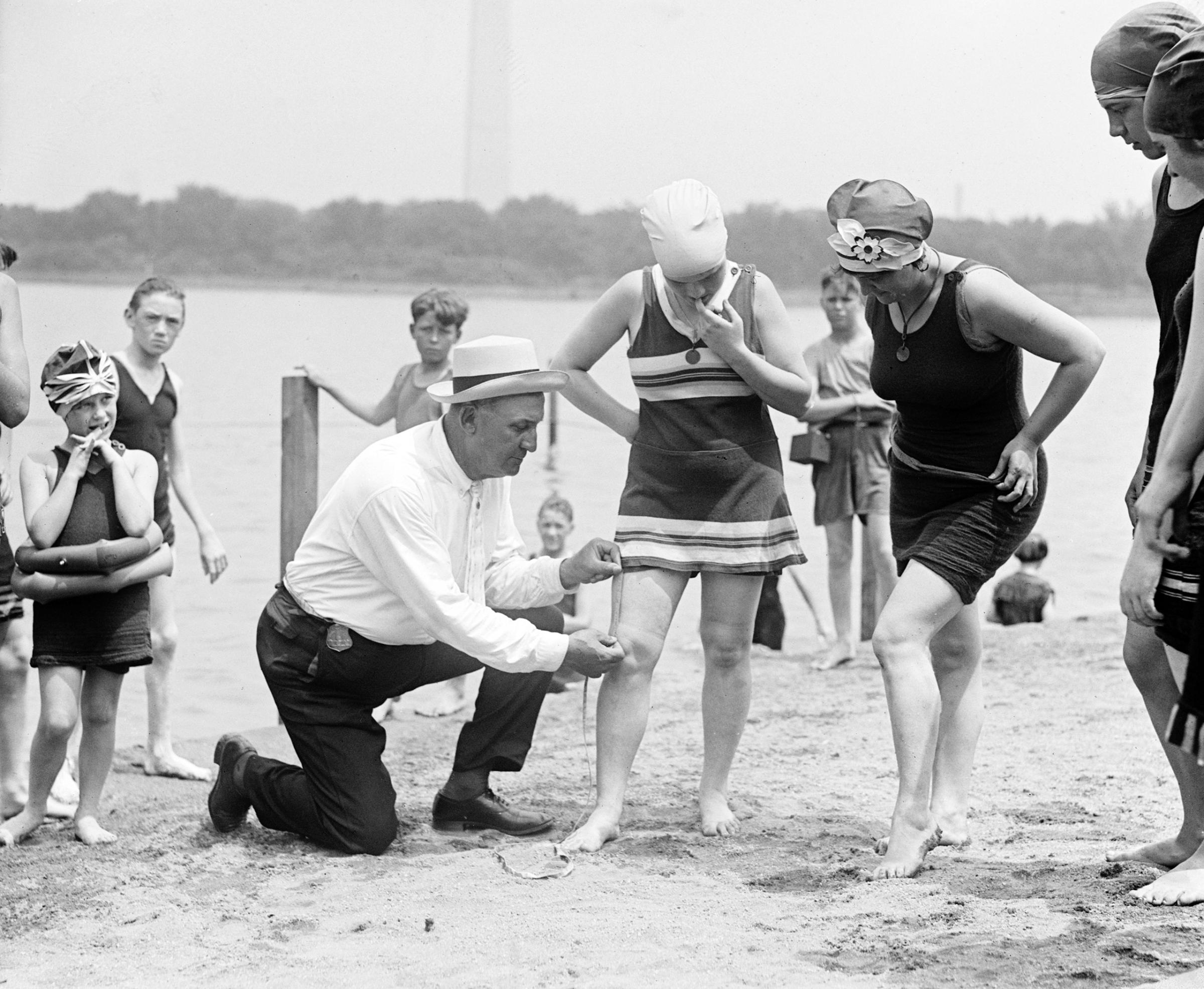 Woman having her swimsuit measured for length violations on a Washington DC beach, circa 1922.