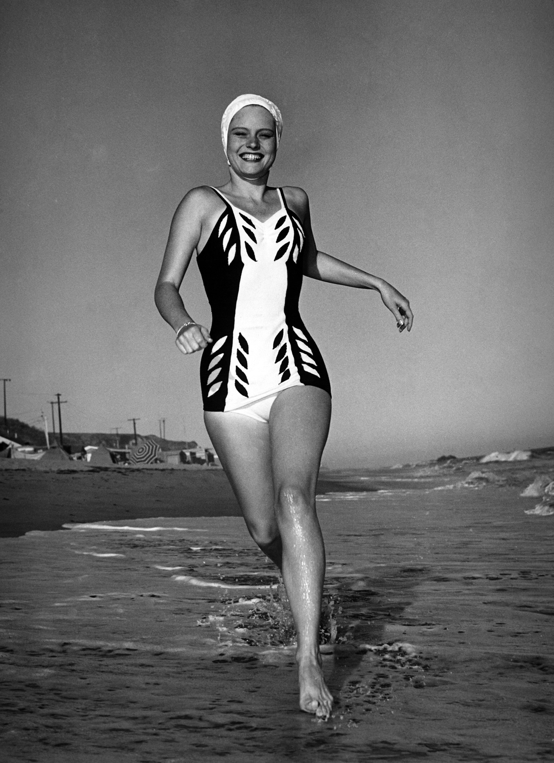 Actress Alexis Smith in a swimming costume running along the beach in southern California, USA circa 1940.