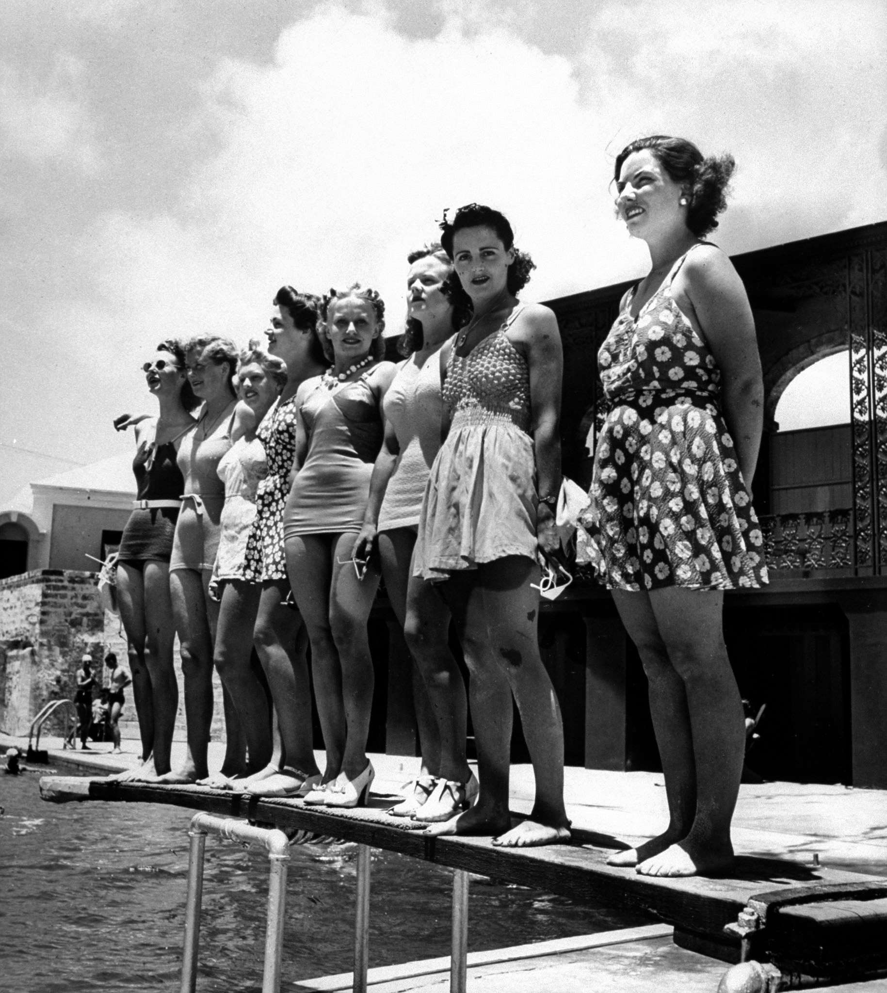 Bathing suit clad female members of the British Imperial Censorship Staff, who call themseleves the censorettes, standing poolside at the Princess Hotel, which also serves as their offices on the island. Circa 1941.