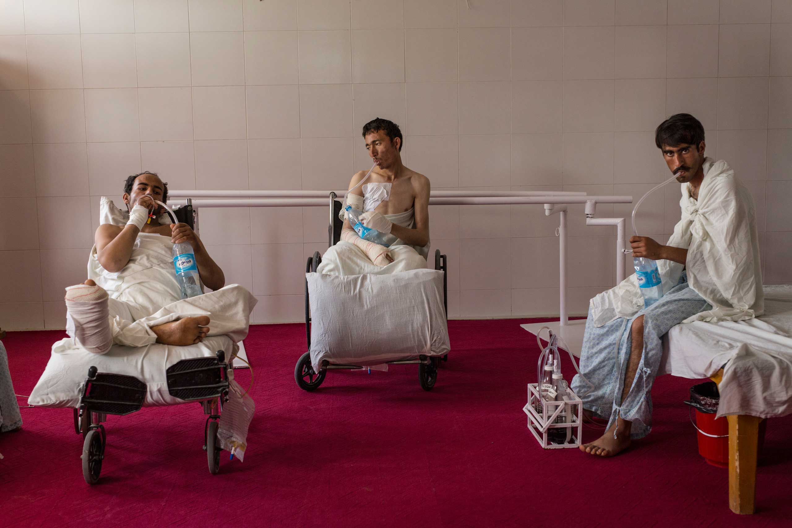 Patients with chest injuries strengthen their lung capacity with water bottles in the physical therapy room at the Emergency hospital in Lashkar Gah, Afghanistan on March 27, 2015.