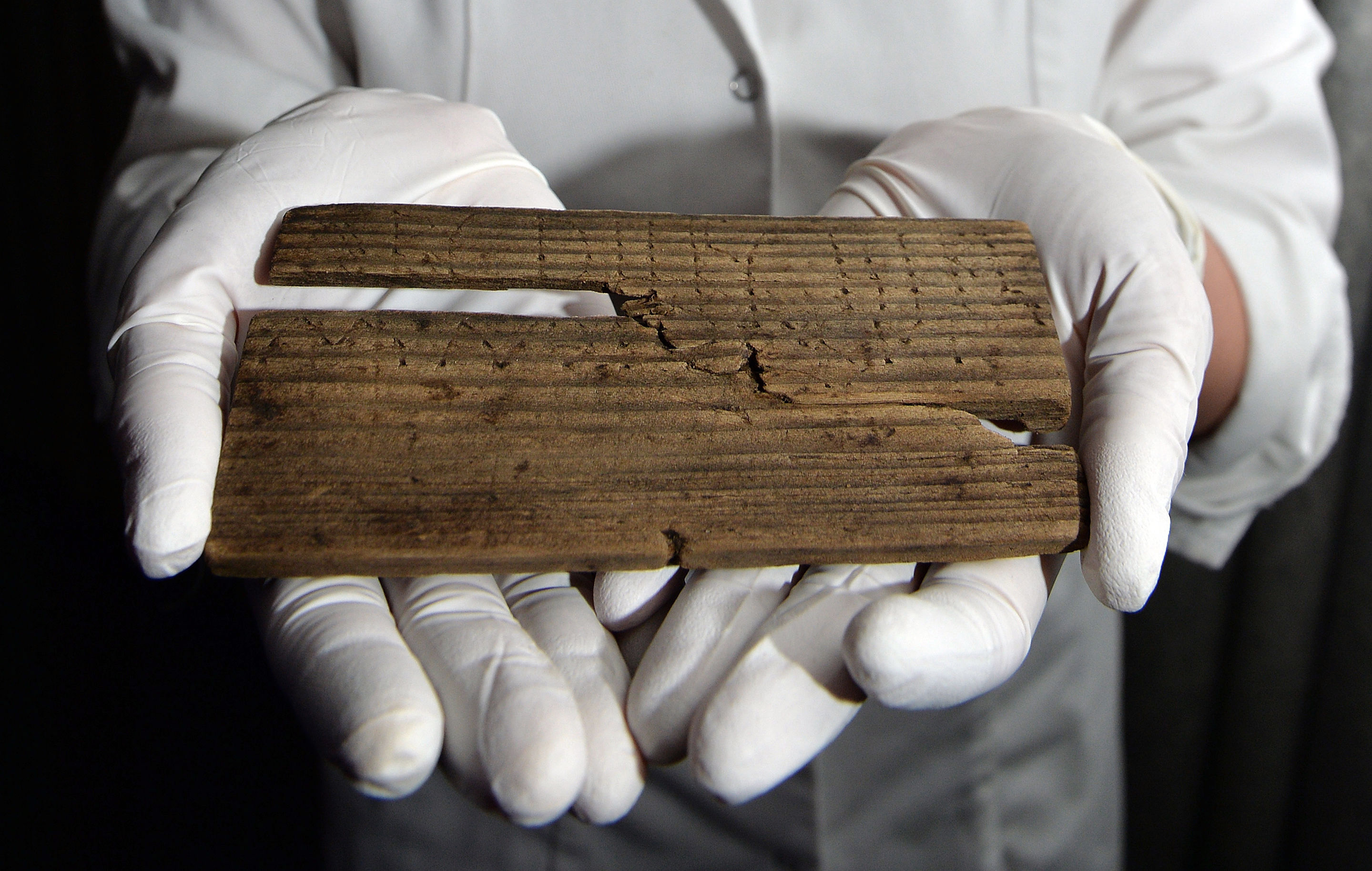 Luisa Duarte, a conservator for the Museum of London, holds a piece of wood with the Roman alphabet written on it in London on June 1, 2016 (John Stillwell&mdash;AP)