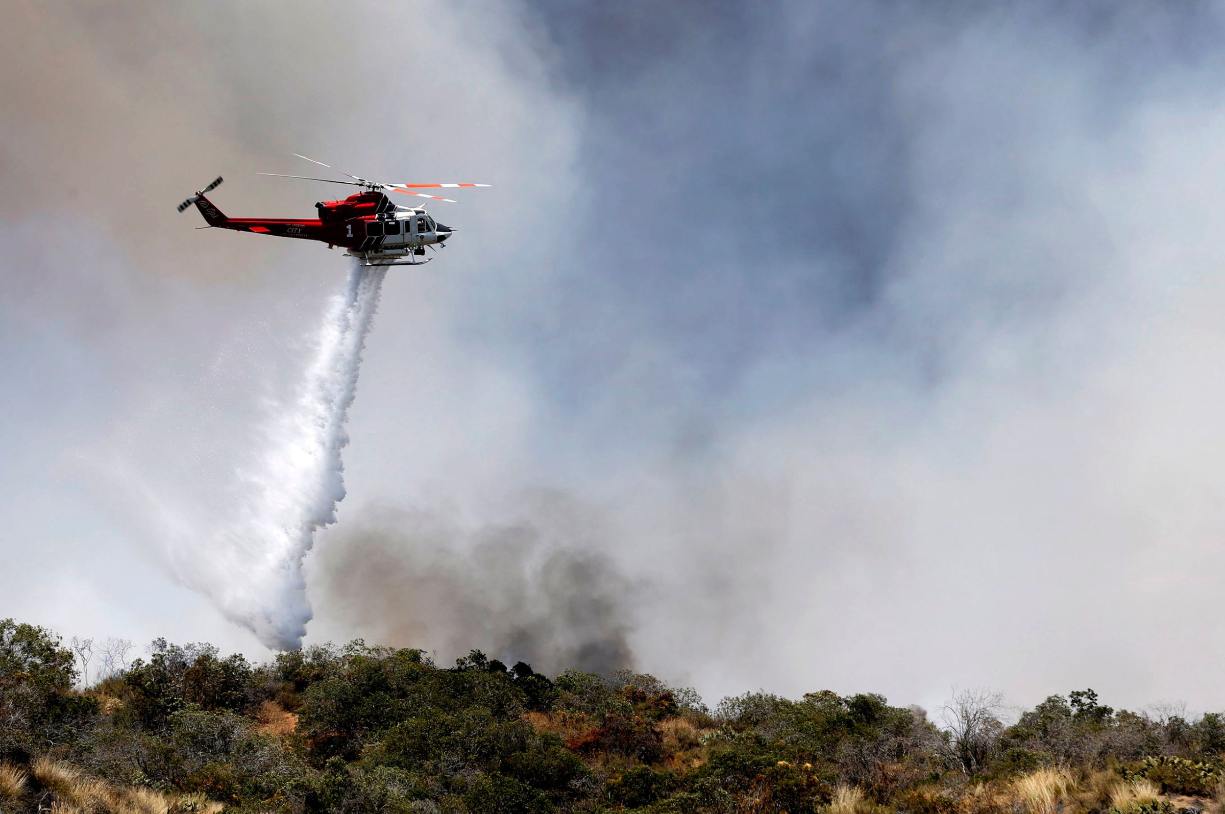 A firefighting helicopter makes a water drop over a wildfire just north of Azusa, Calif., Monday, June 20, 2016. Two fires have erupted in the San Gabriel Mountains northeast of Los Angeles amid withering heat. The first fire reported Monday was near Morris Reservoir north of suburban Azusa. AP Photo/Nick Ut)