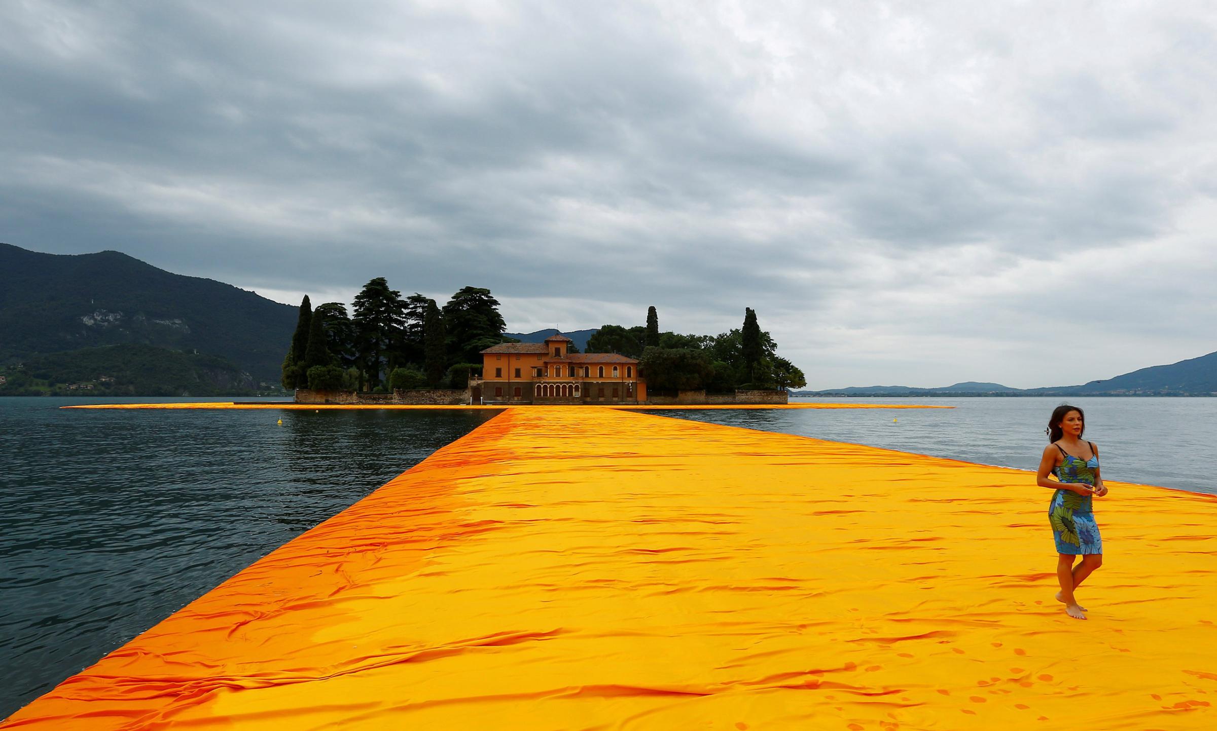 A woman walks on the installation 'The Floating Piers' by Bulgarian-born artist Christo Vladimirov Yavachev known as Christo, on the Lake Iseo, northern Italy on June 16, 2016.