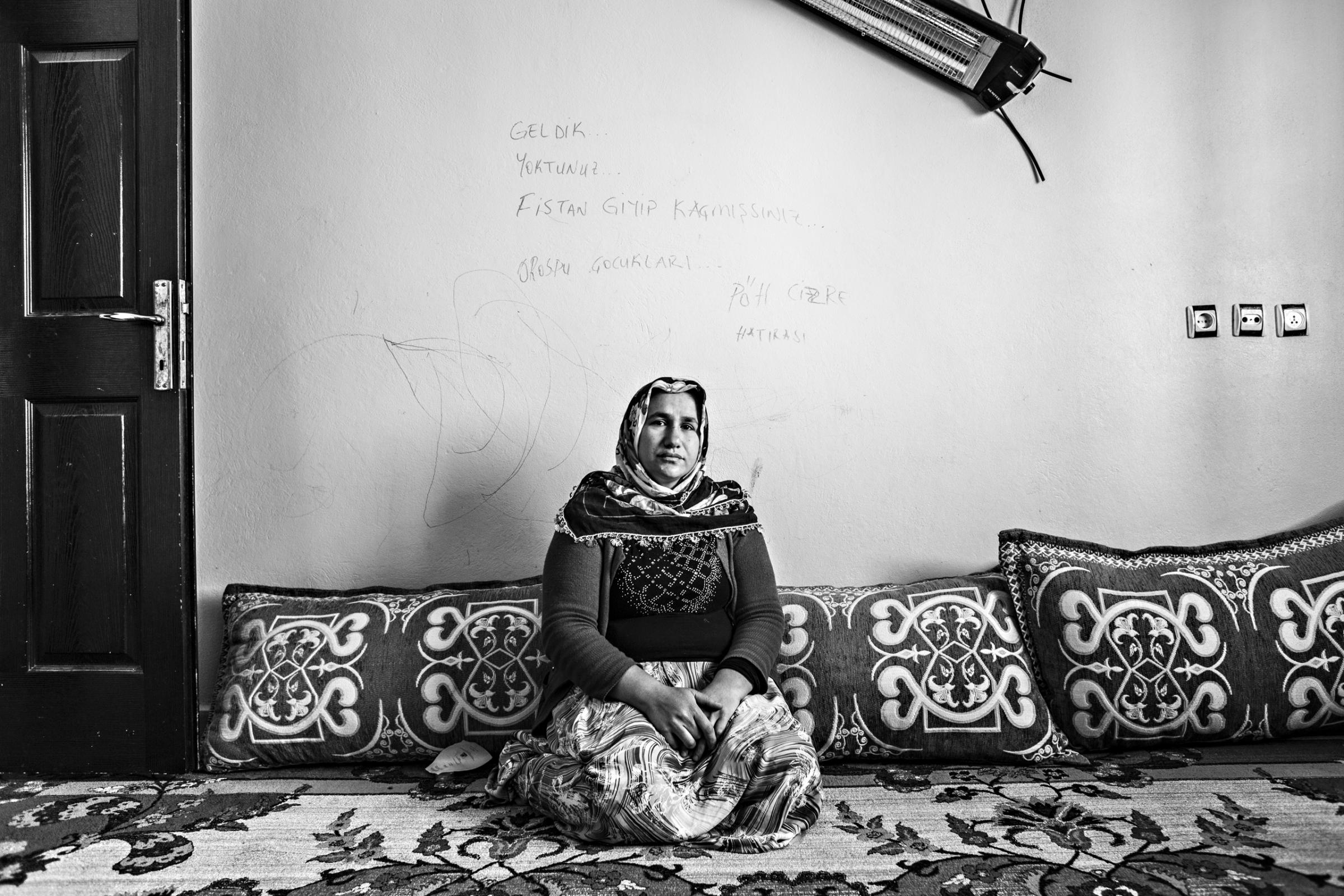 Fatma Tetik sits near a wall with threatening graffiti written by Turkish special forces. Her husband, Ali Tetik, was killed during fighting between Turkish special forces and PKK (Kurdistan Workers Party), Cizre, March 2016.