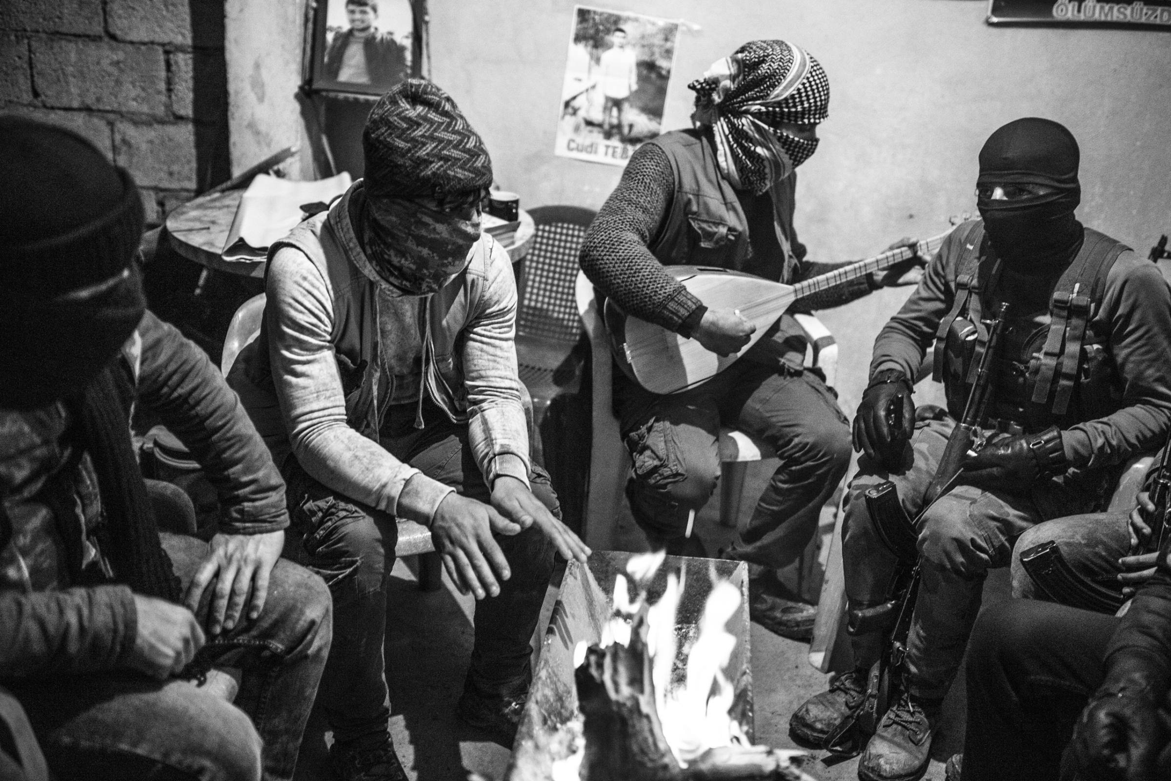 Members of the Civil Protection Units (YPS), a Kurdish rebel group, warm up and play music near a fire in the YPS headquarters in Nusaybin, Turkey, Jan. 2016. The YPS was formed at the end of 2015 as a result of curfews imposed by the Turkish security forces and increased clashes.