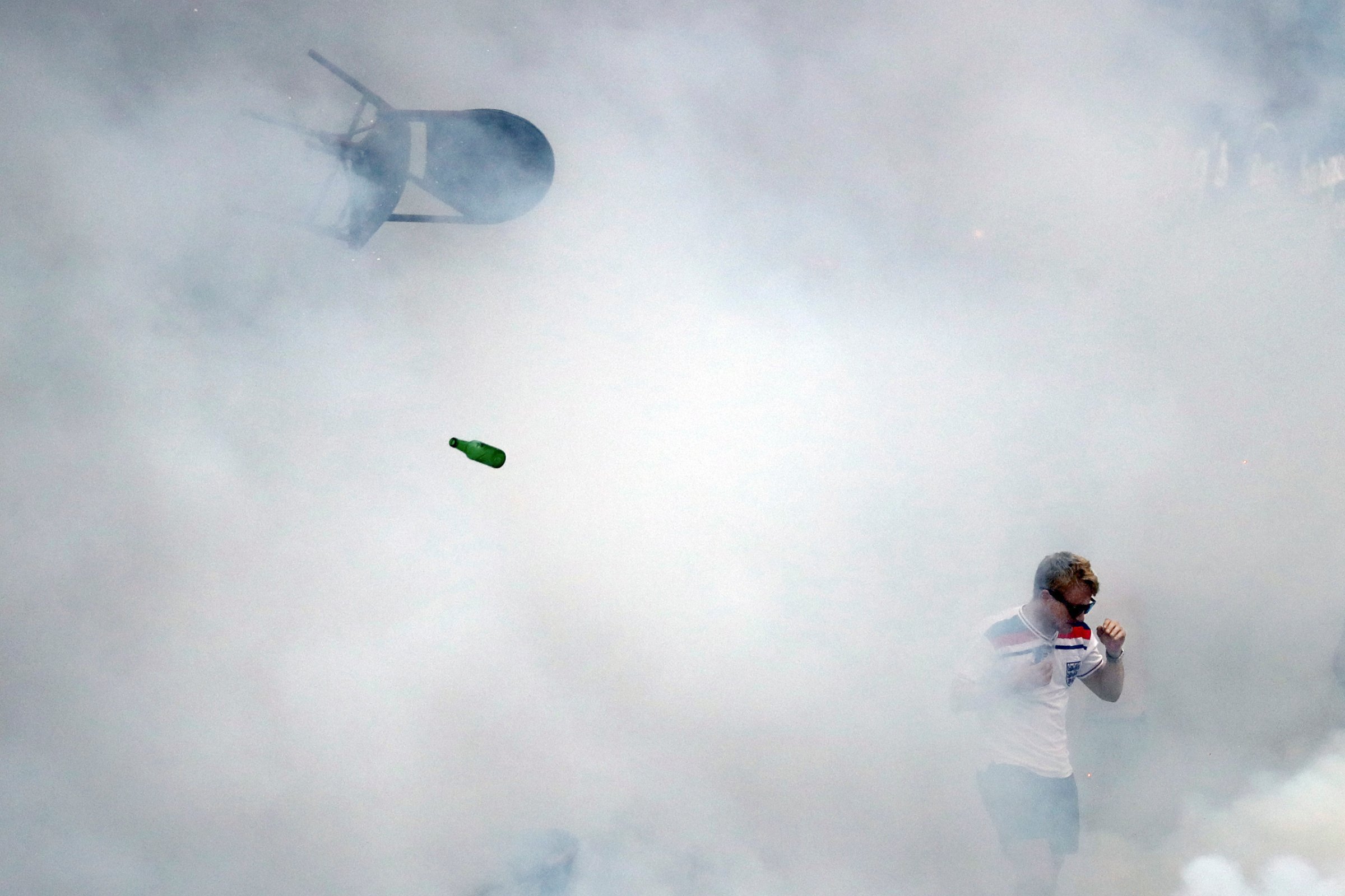 A bottle and chair are thrown as an England fan walks through tear gas as England fans clash with police in Marseille, France, on June 10, 2016.