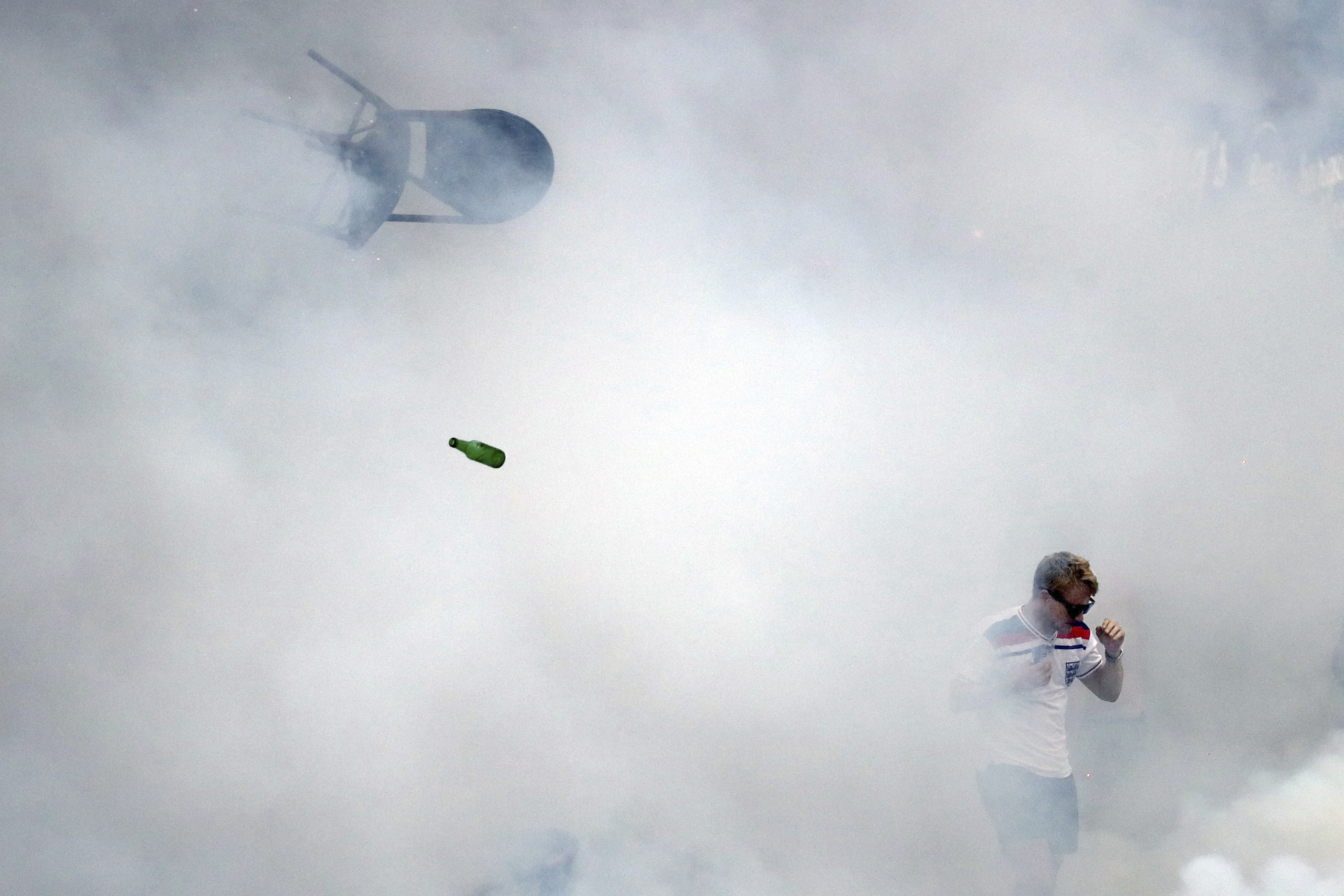 A bottle and chair are thrown as an England fan walks through tear gas as England fans clash with police in Marseille, France, on June 10, 2016. (Carl Court—Getty Images)