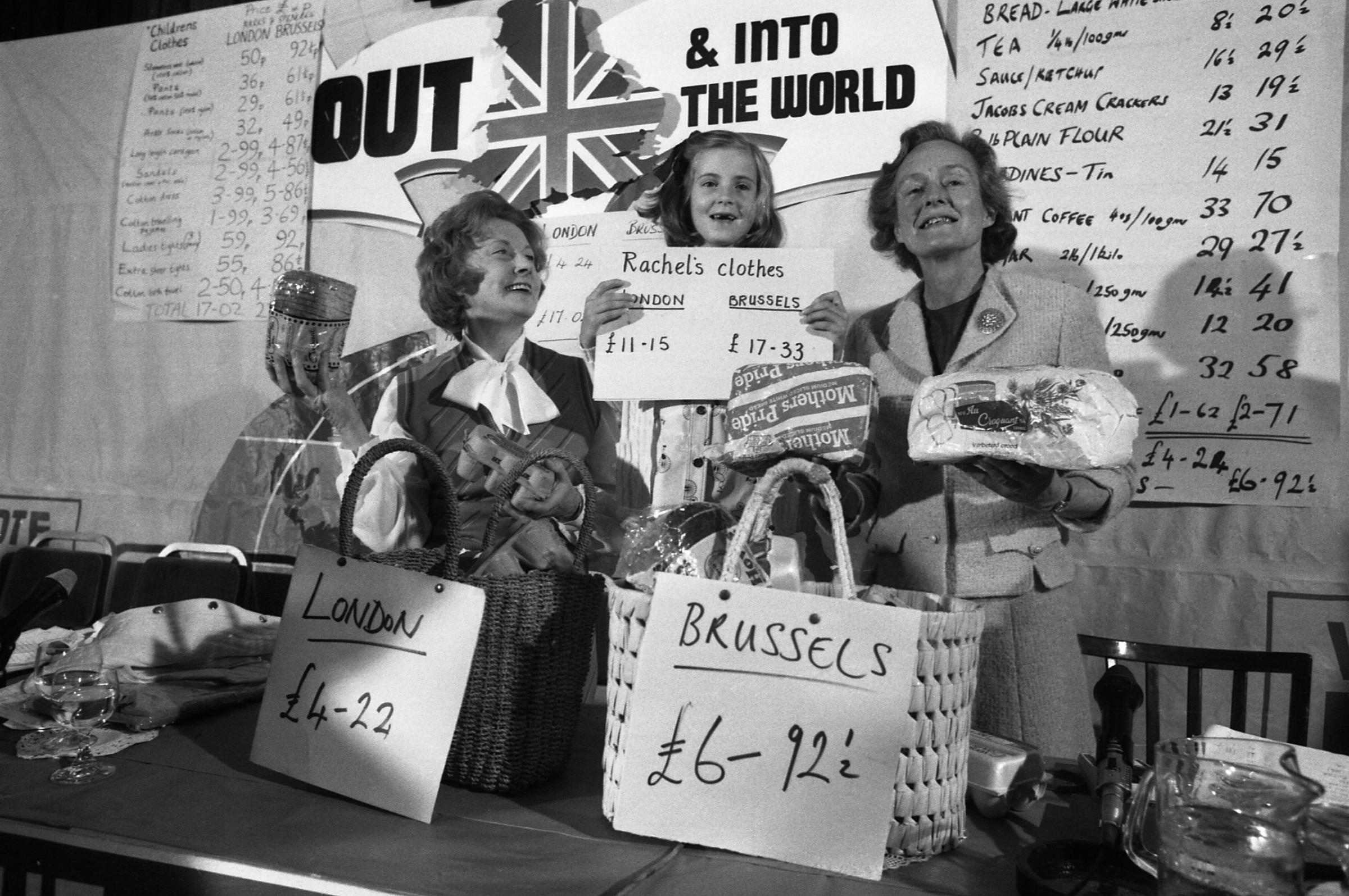 Social Services secretary, Mrs Barbara Castle, left, her seven year old great-niece Rachel Hilton and Mrs Joan Marten, wife of Neil Martin, Chairman of the anti-Common Marketeers (unseen) display goods they brought in London and Brussels with their retrospective prices for comparison during a press conference at the Waldorf Hotel in London, England , May 29, 1975.