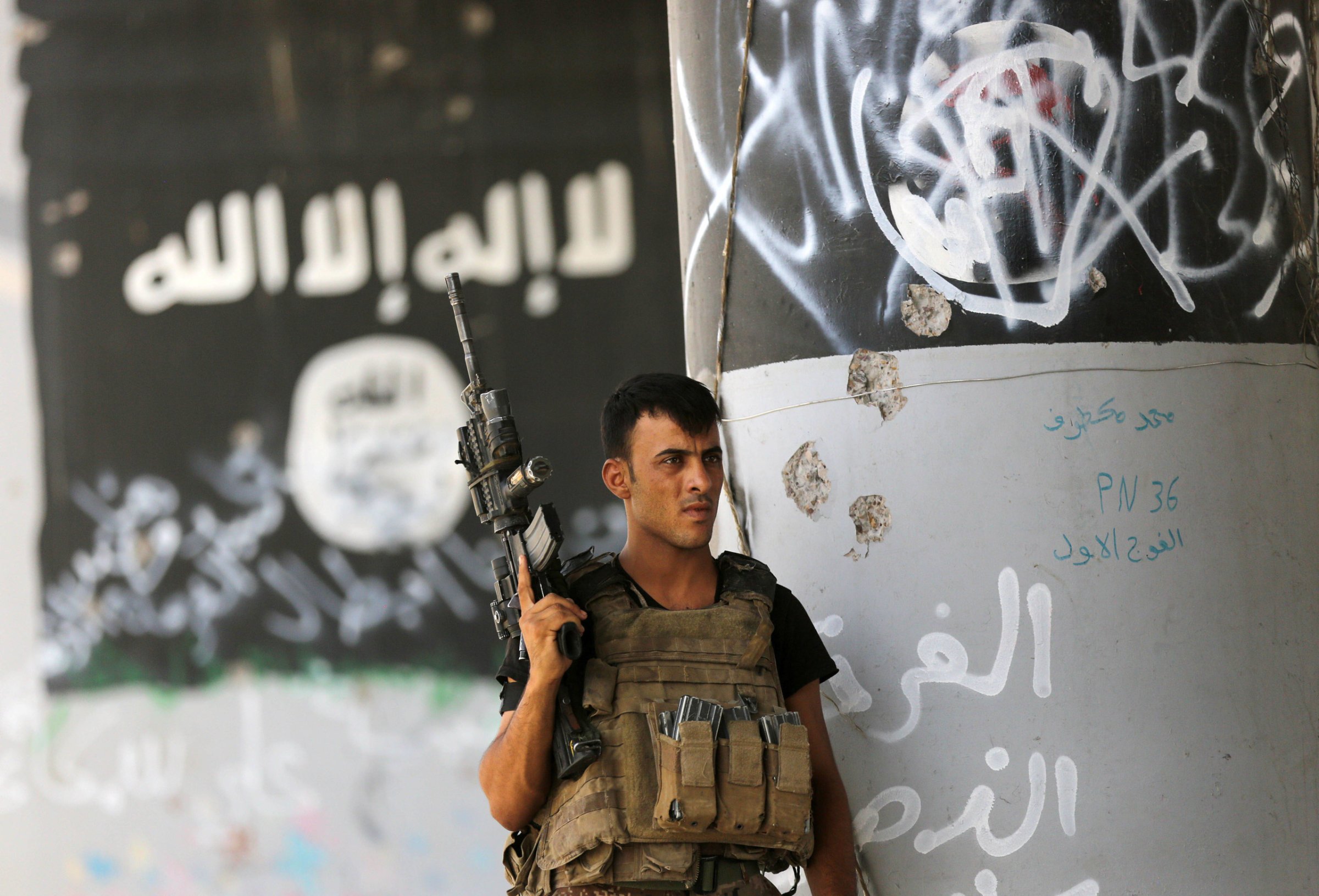 A member of Iraqi counterterrorism forces stands guard near Islamic State militant graffiti in Fallujah, Iraq, Monday, June 27, 2016. Thick clouds of black smoke billowed over northwest Fallujah Monday as dozens of homes continued to burn a day after the city was declared ‚Äúfully liberated‚Ä˘ from the Islamic State group. Iraqi special forces Lt. Gen. Abdel Wahab al-Saadi who led the operation to retake the city, said that IS militants torched hundreds of houses in Fallujah's north and west as they fled Sunday, just as the fighters did in many of the city's other neighborhoods over the course of the operation. Partial translation of Arabic writing on the wall reads, "patience honorable Fallujah, victory is near." (AP Photo/Hadi Mizban)