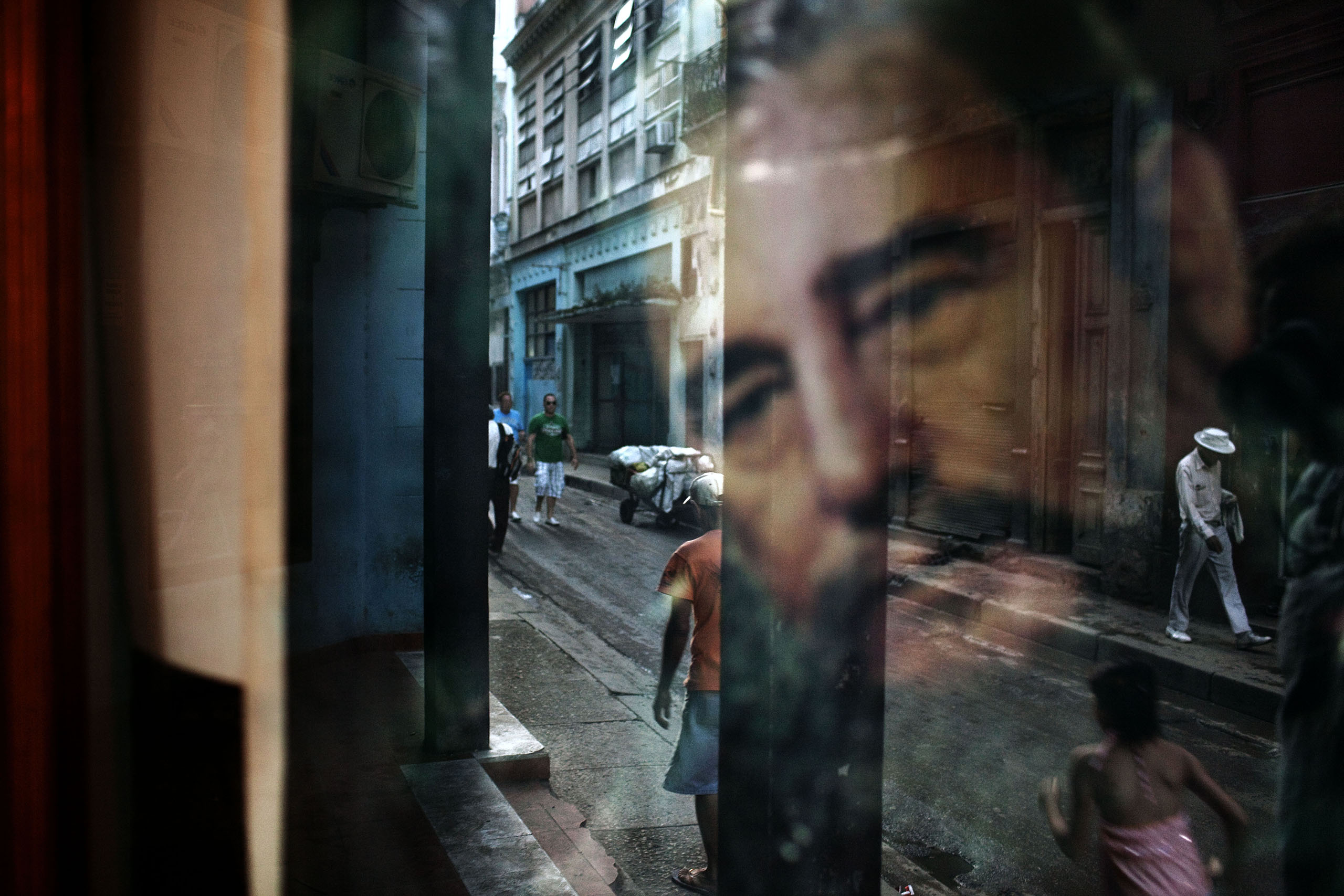 A window reflects an image of Fidel Castro in a working-class Havana neighborhood that attracts few tourists.