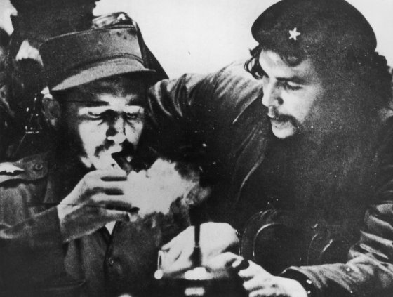 Cuban revolutionary Fidel Castro (left) lights his cigar while Argentine revolutionary Che Guevara looks on in the early days of their guerrilla campaign in the Sierra Maestra Mountains of Cuba, circa 1956. Castro wears a military uniform while Guevara wears fatigues and a beret.