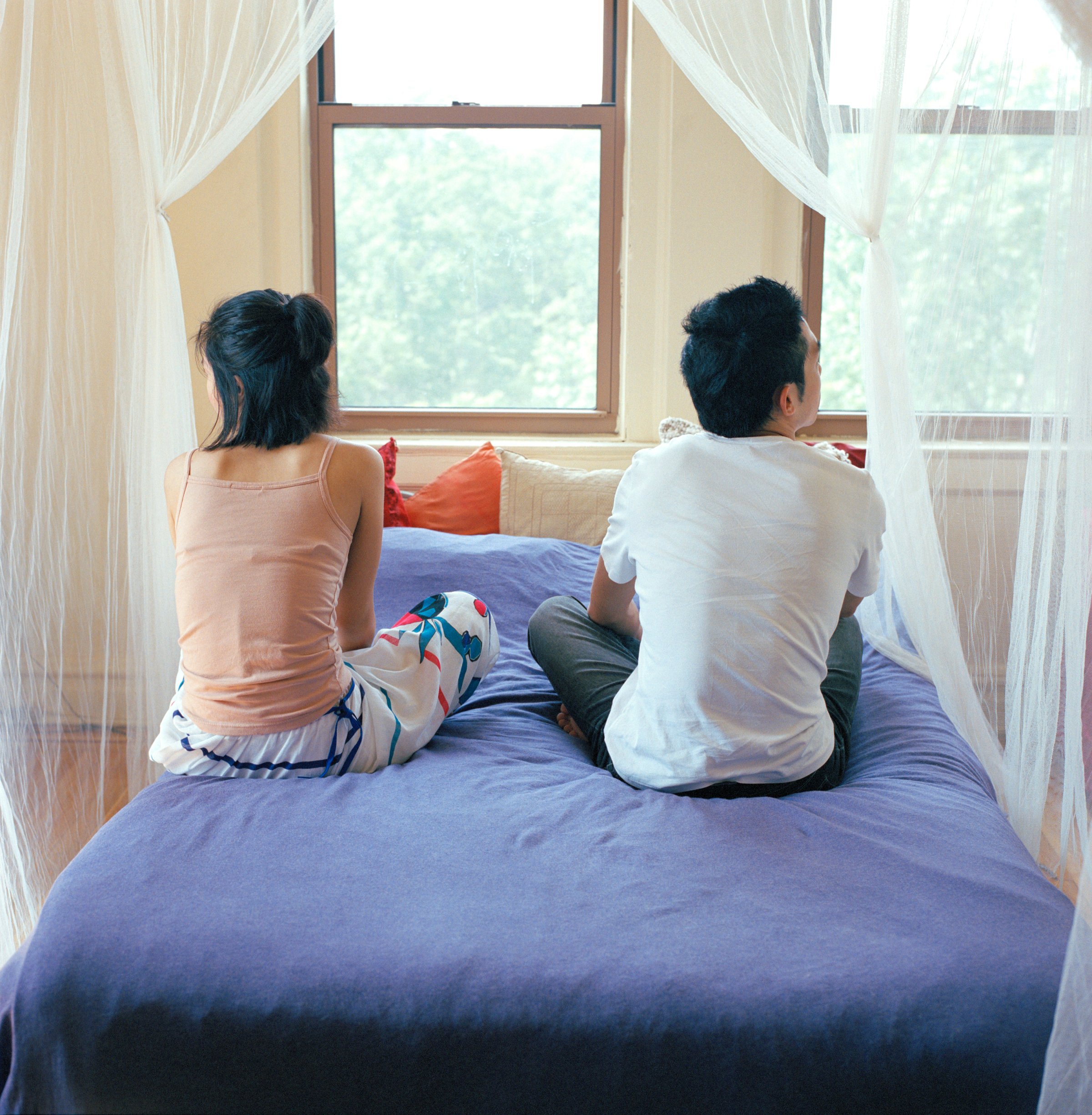 Young couple sitting on bed, rear view
