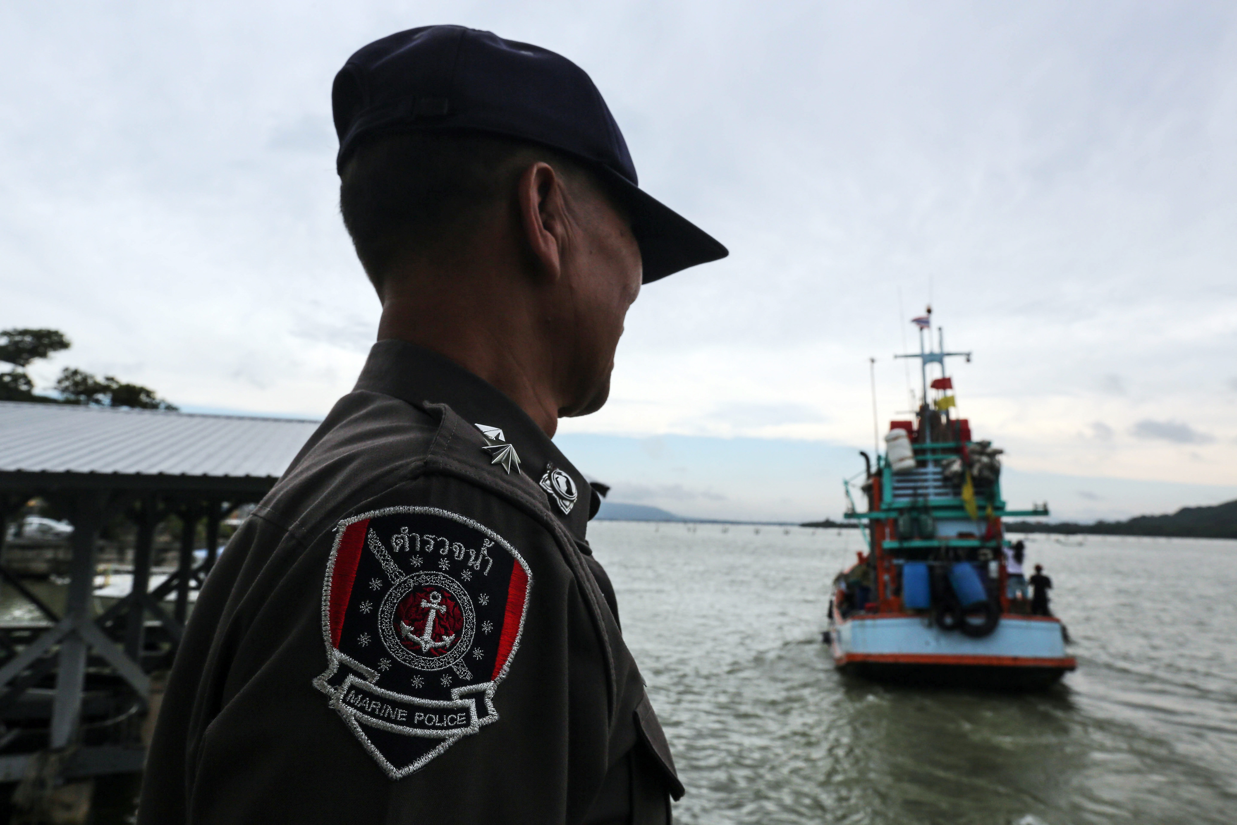 A Royal Thai Maritime Police officer watches a fishing boat leave Songkhla port in Songkhla, Thailand, on Dec. 23, 2015 (Bloomberg—Bloomberg via Getty Images)