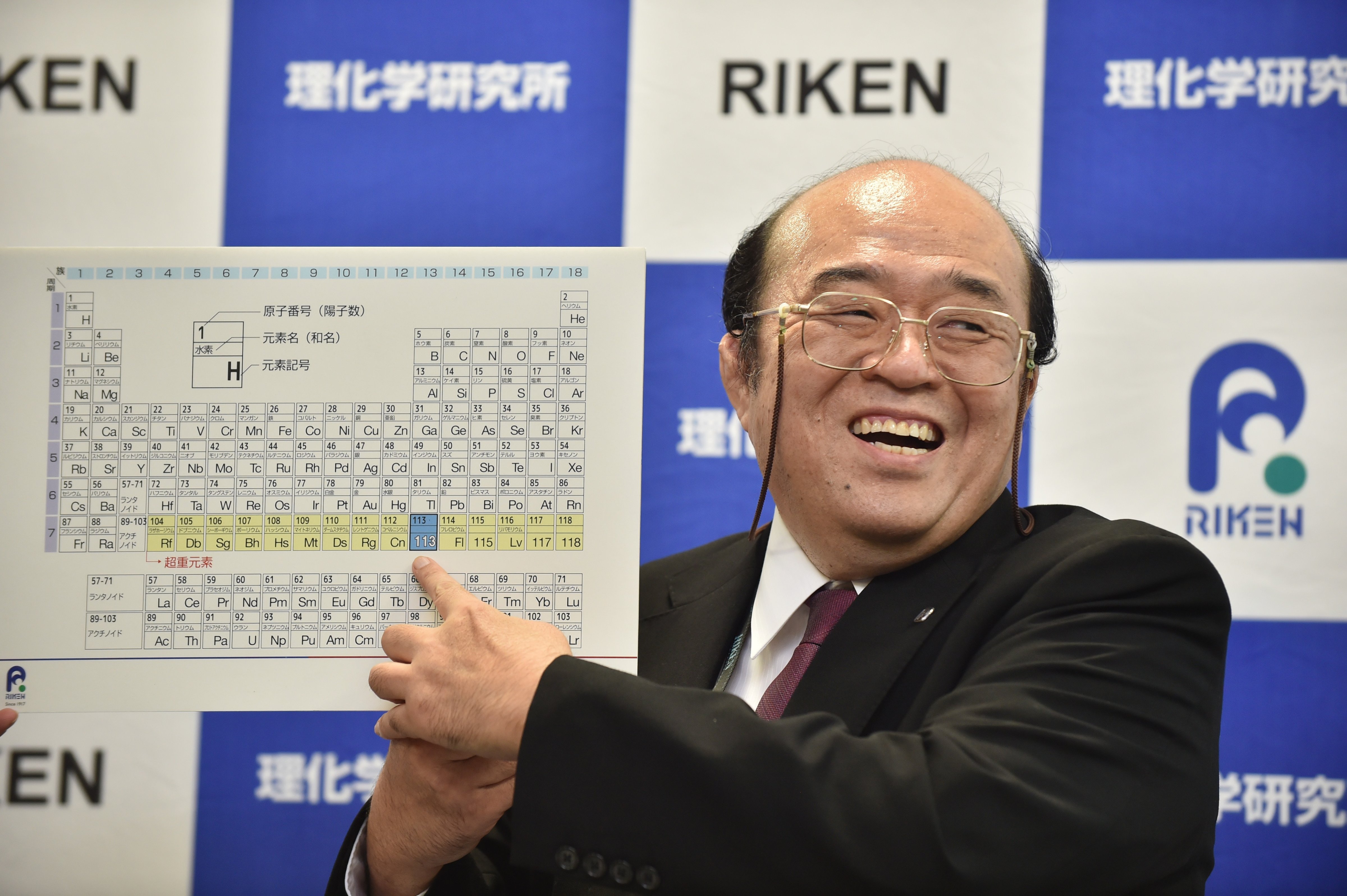 Kosuke Morita, the leader of the Riken team, smiles as he points to a board displaying the new atomic element 113 during a press conference in Wako, Saitama prefecture on December 31, 2015 (Kazuhiro Nogi—AFP/Getty Images)