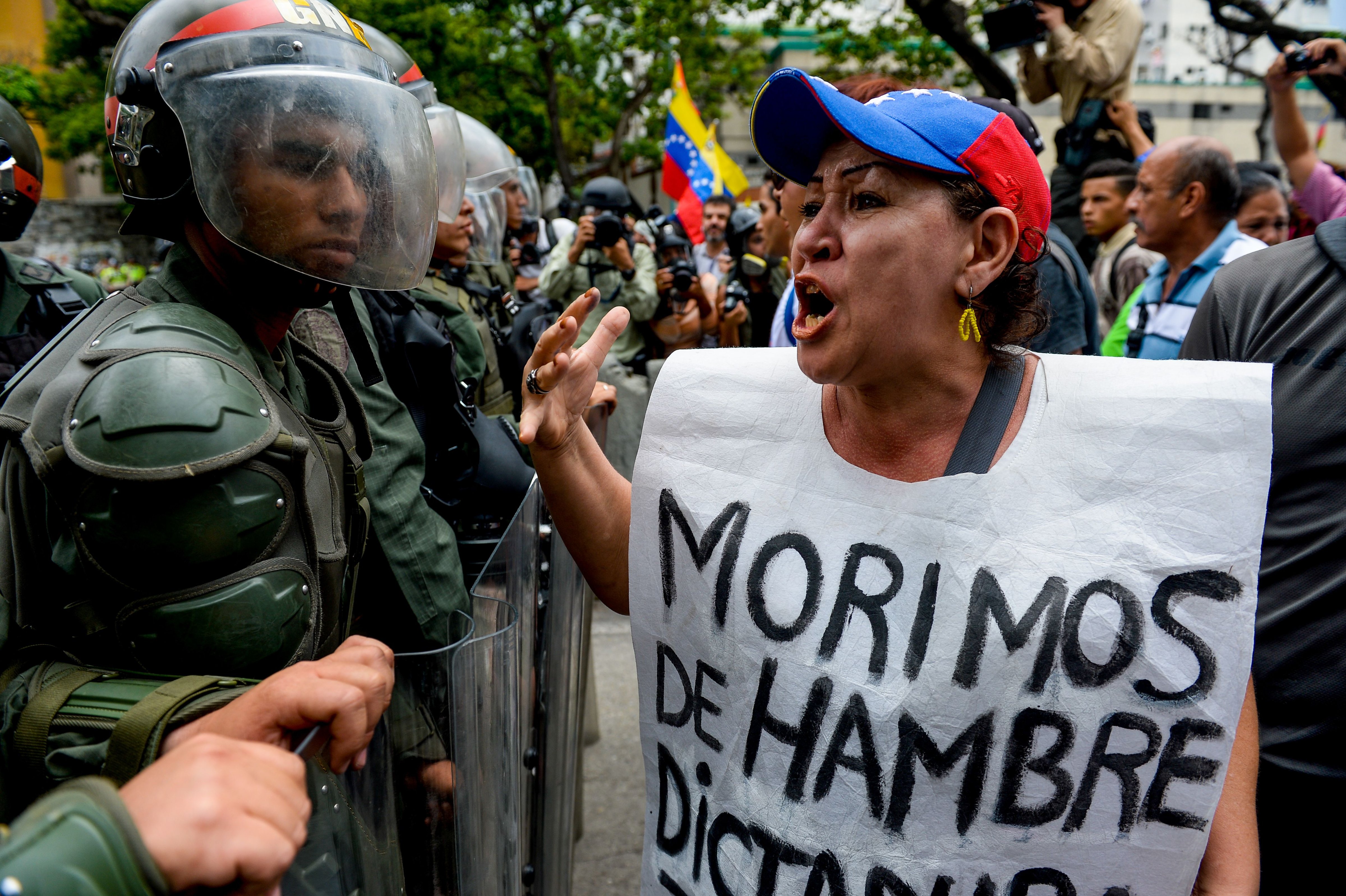 A woman with a sign reading "We starve" protests against new emergency powers decreed by President Nicolas Maduro in front of a line of riot policemen in Caracas on May 18, 2016. (FEDERICO PARRA—AFP/Getty Images)