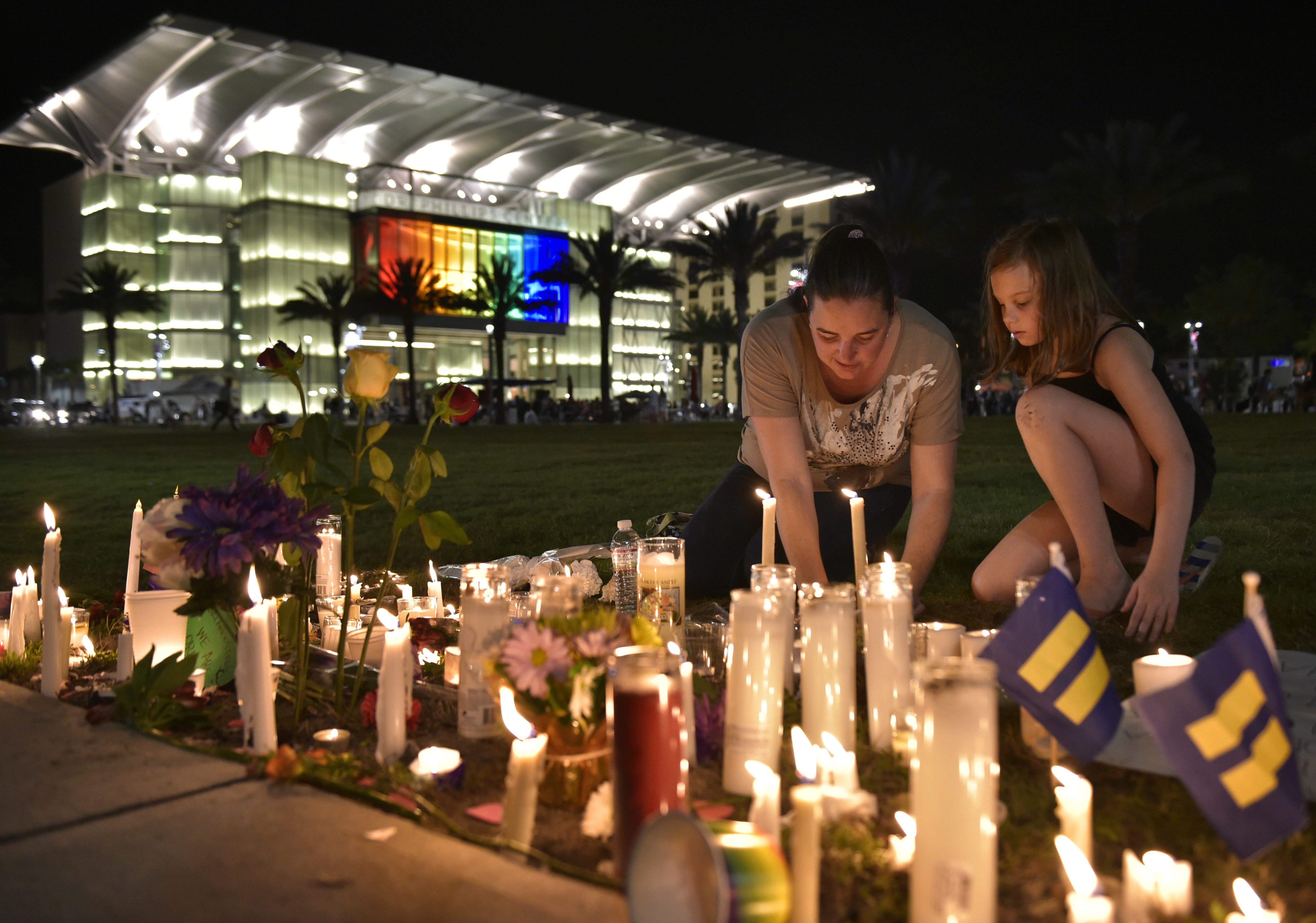 A woman and child arrange candles for the victims of the Pulse nightclub shooting, following a vigil on June 13, 2016 at the Dr. Phillips Center for the Performing Arts in Orlando, Florida. (MANDEL NGAN—AFP/Getty Images)