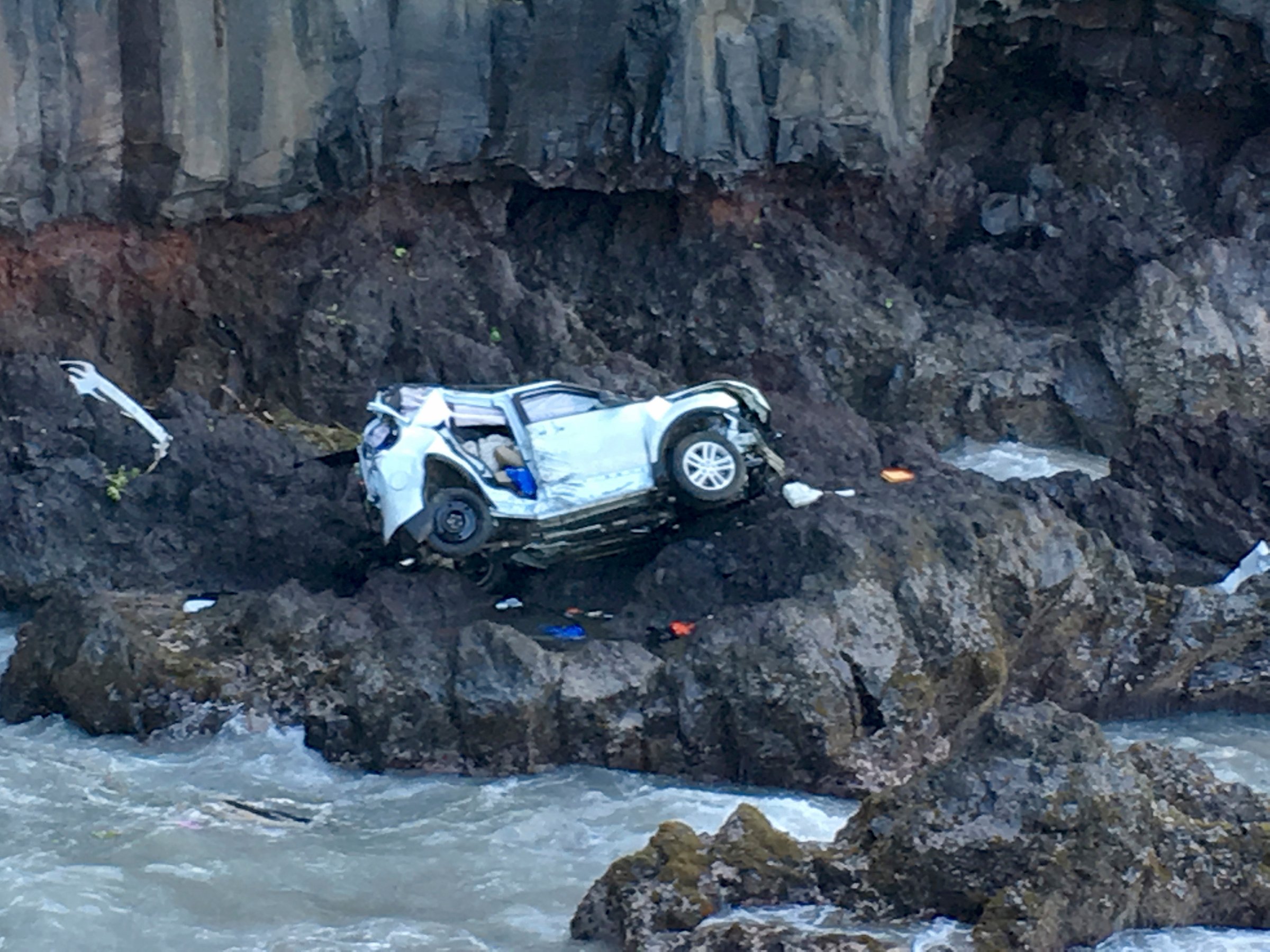 In this May 29, 2016, photo provided by Tom Johnson, a vehicle sits at the bottom of a cliff off Maui’s Hana Highway in Hana, Hawaii. Police say the Ford Explorer fell about 200 feet. Prosecutors say Alexandria Duval, who is also known as Alison Dadow, intentionally caused the death of her sister, Anastasia Duval, also known as Ann Dadow.