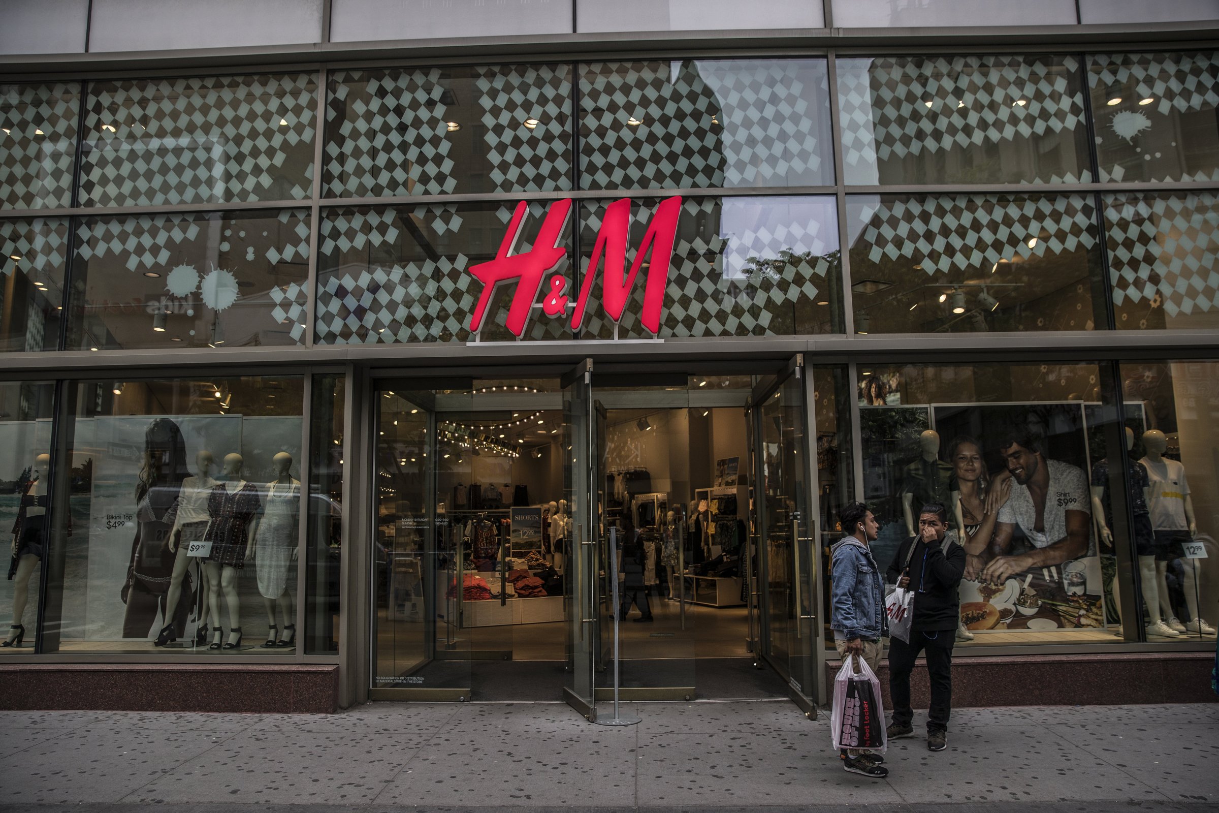 Shoppers stand outside a Hennes &Mauritz AB (H&M) store along the Fulton Street Mall in the Brooklyn borough of New York, U.S, on Friday, May 13, 2016.