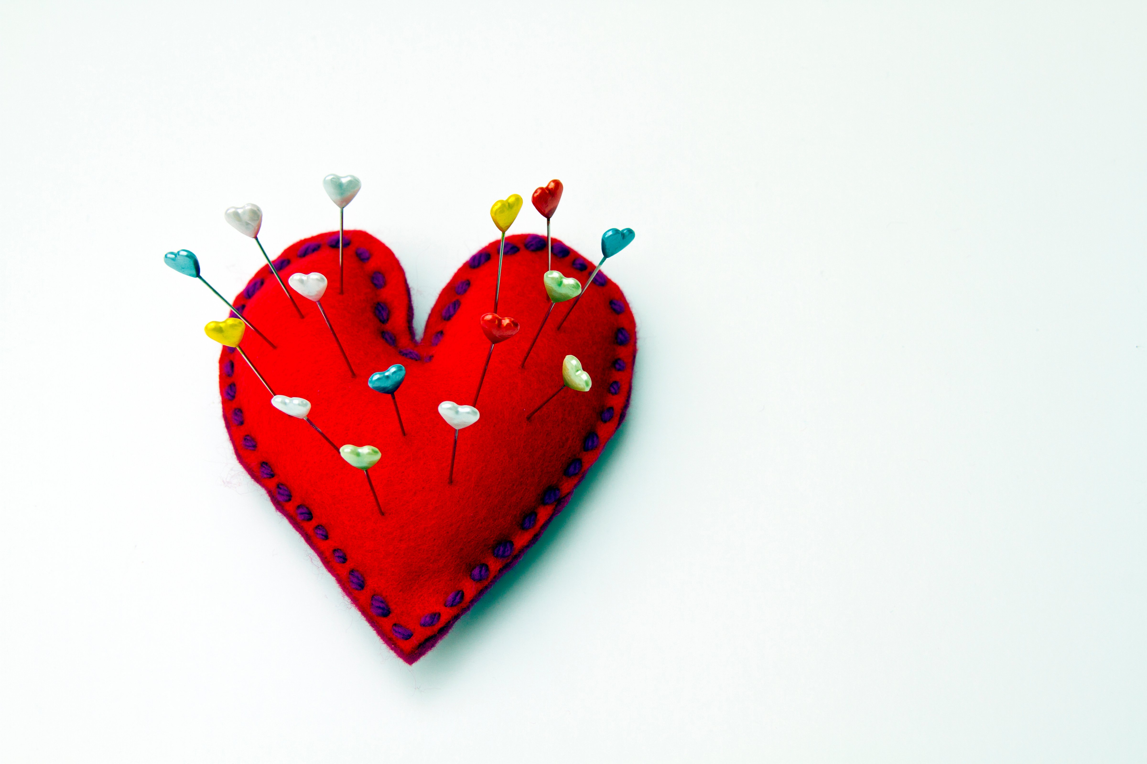 Red felt heart shaped pin cushion with heart topped pins inserted. (Catherine MacBride—Getty Images)