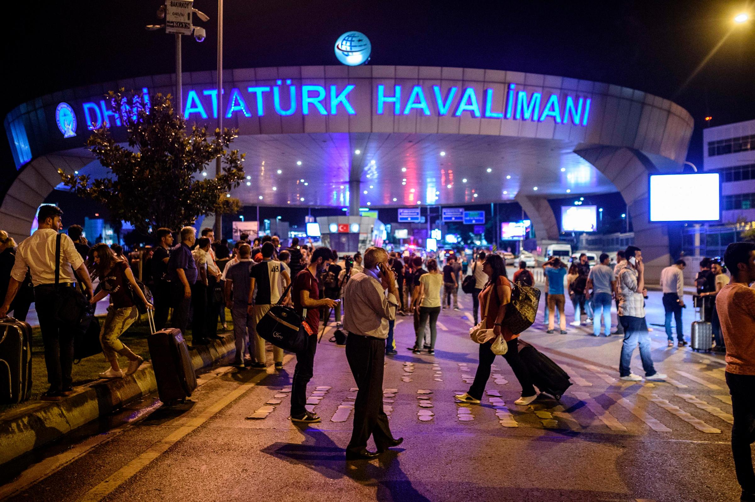People stand outside the entrance as they leave Istanbul's Ataturk airport after at least two explosions on June 28, 2016.