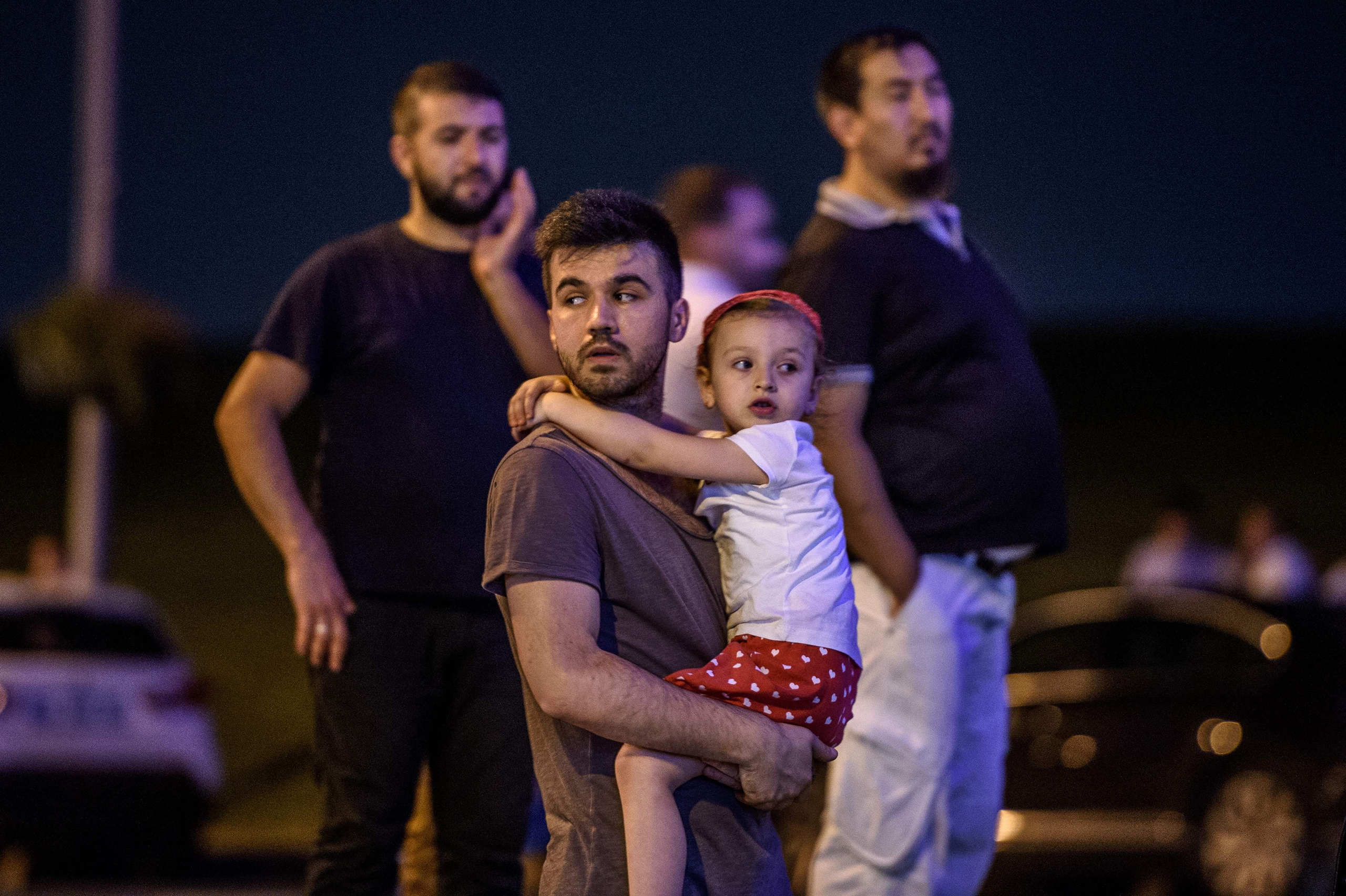 A man carries his daughter outside as people leave the Istanbul Ataturk airport after an attack on June 28, 2016.