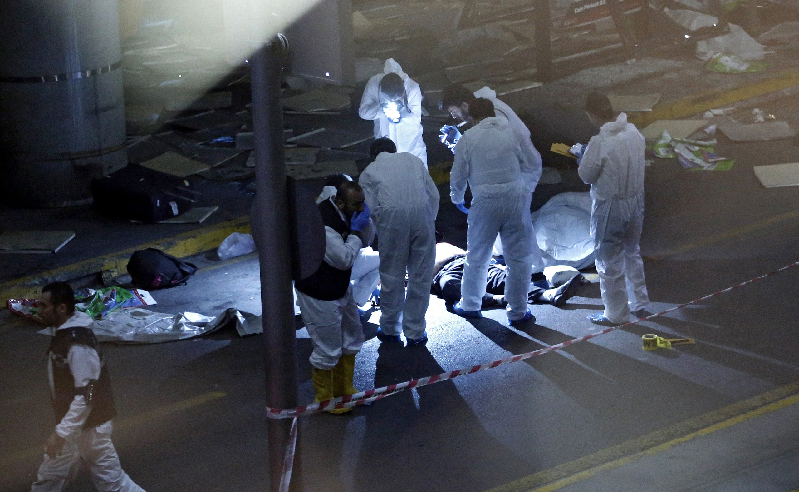 Crime scene investigators work next to a body after a suicide bomb attack at Ataturk Airport in Istanbul on June 28, 2016.