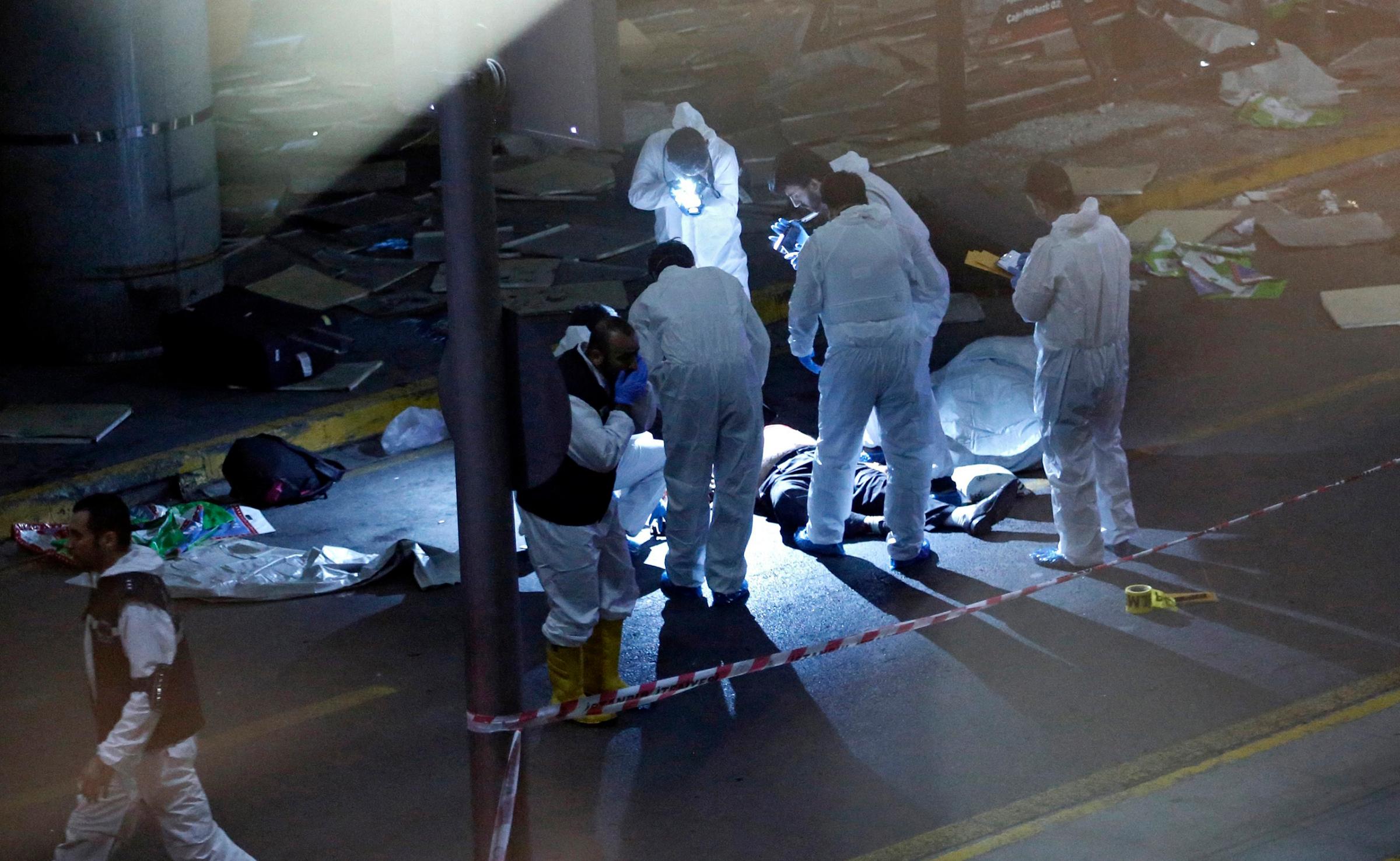 Crime scene investigators work next to a body after a suicide bomb attack at Ataturk Airport in Istanbul on June 28, 2016.