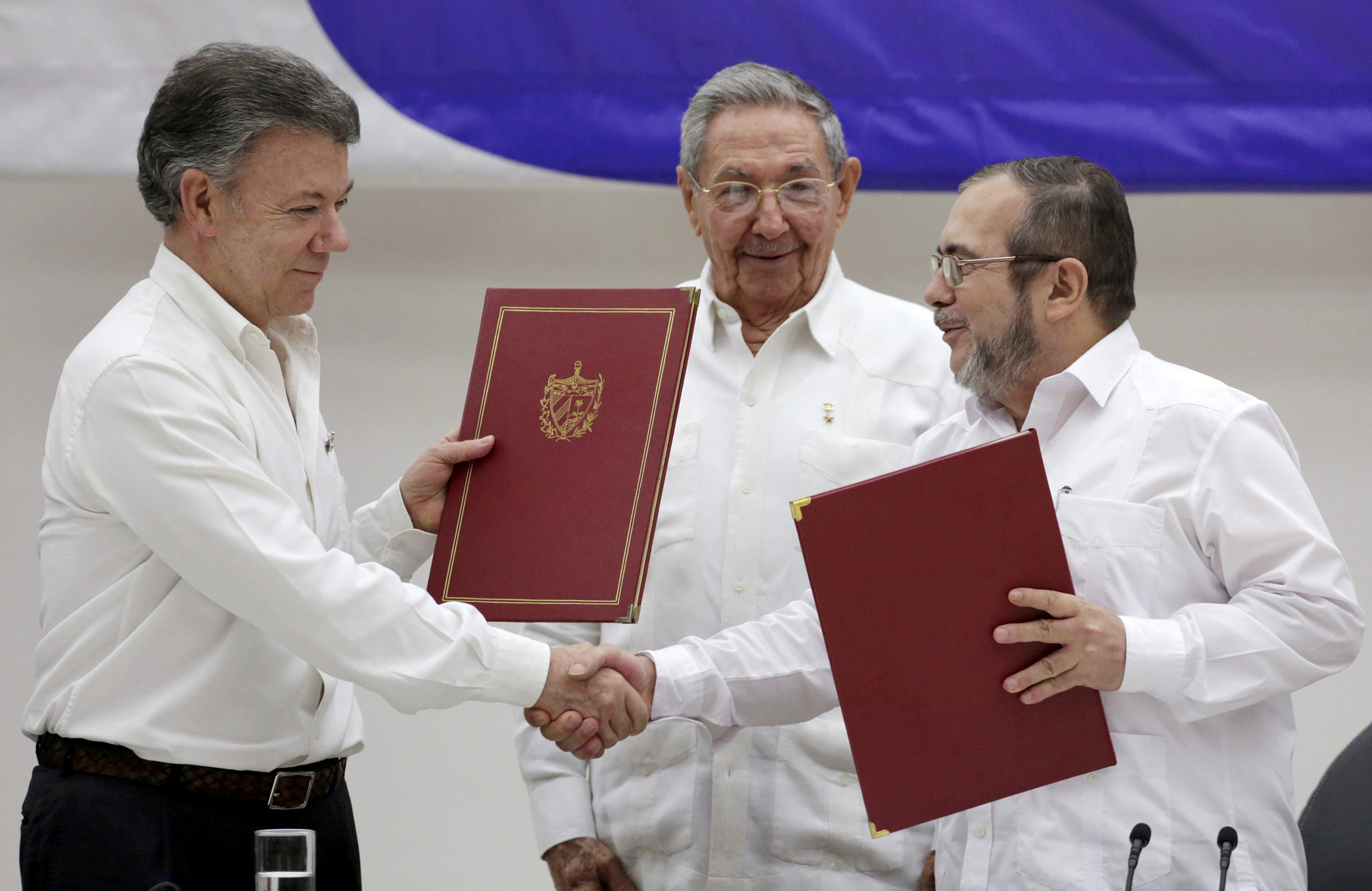 Colombia's President Juan Manuel Santos, left, shakes hands with FARC rebel leader Rodrigo Londono, better known by his nom de guerre Timochenko, right, as Cuba's President Raul Castro looks on after the signing of a historic ceasefire deal between the Colombian government and FARC rebels in Havana, Cuba, on June 23, 2016. (Enrique de la Osa—Reuters)