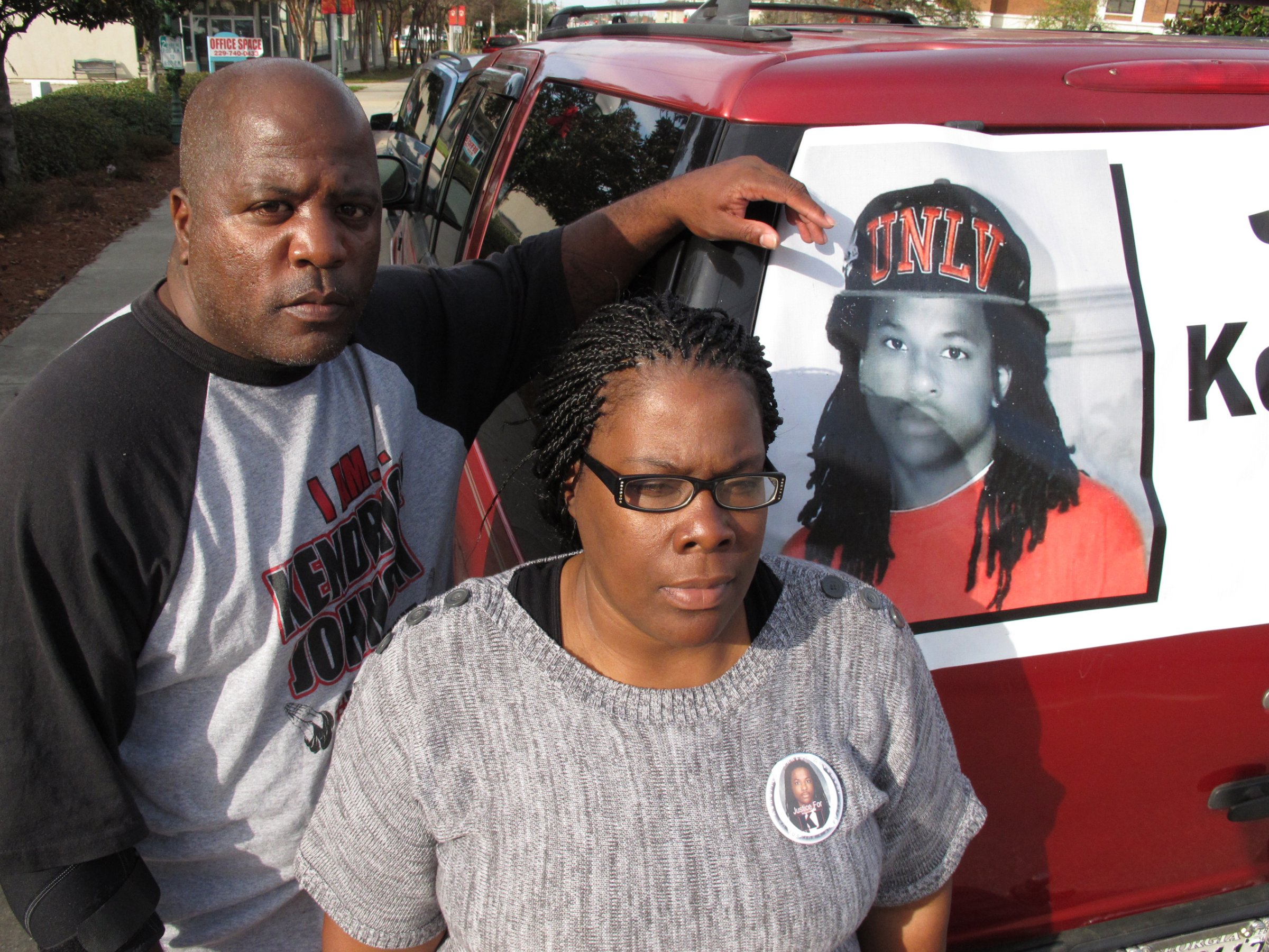 FILE- In this Dec. 13, 2013 file photo, Kenneth and Jacquelyn Johnson stand next to a banner on their SUV showing their late son, Kendrick Johnson in Valdosta, Ga. The parents of Kendrick Johnson, who was found dead inside a rolled-up gym mat at school, have dropped a wrongful death lawsuit accusing two brothers of killing their son. Chevene King, the Johnsons’ attorney, told The Valdosta Daily Times, Tuesday, March 1, 2016, the family eventually plans to refile the lawsuit. (AP Photo/Russ Bynum, File)