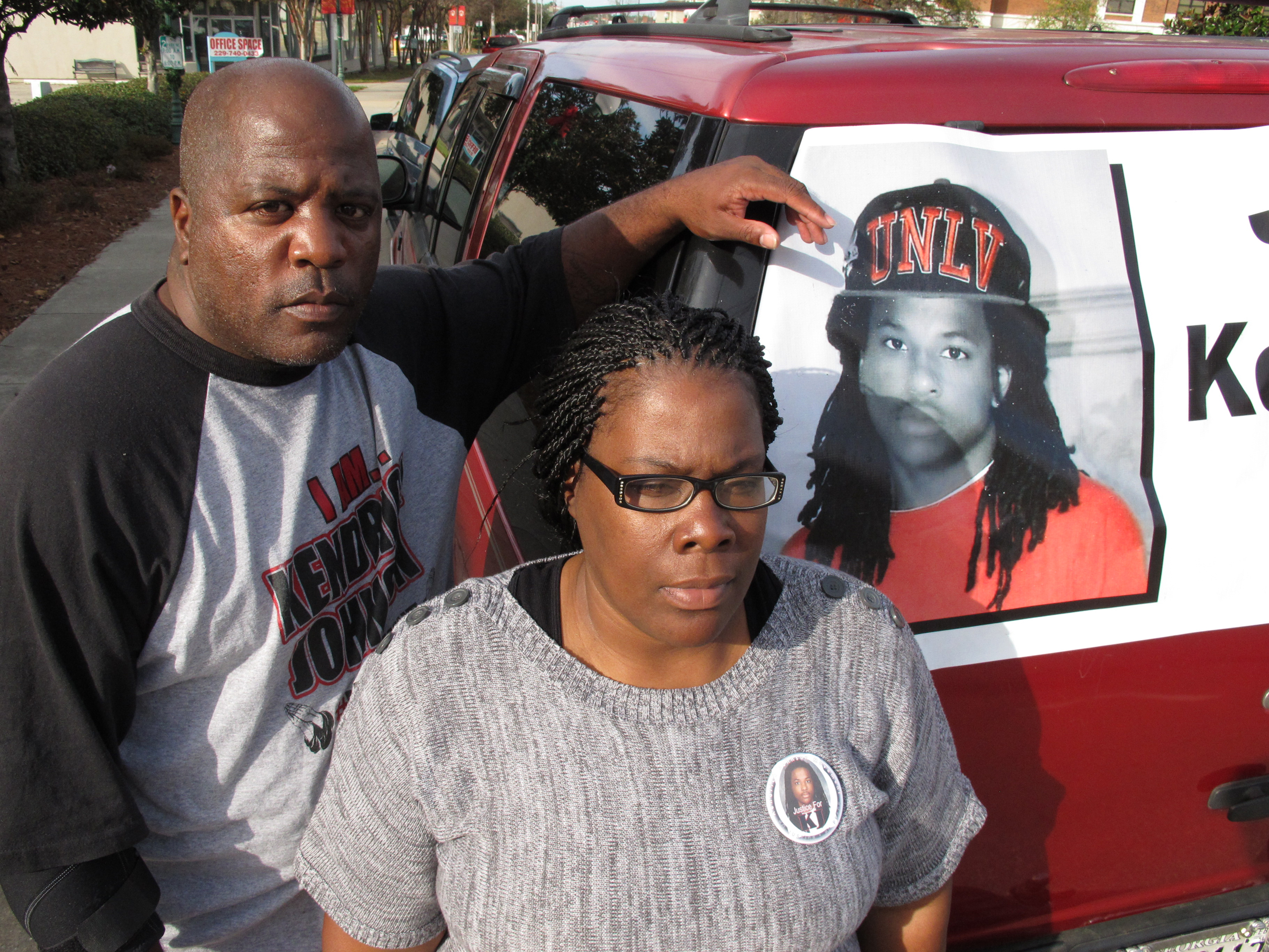 Kenneth and Jacquelyn Johnson stand next to a banner on their SUV showing their late son, Kendrick Johnson in Valdosta, Ga., on Dec. 13, 2013. (Russ Bynum—AP)