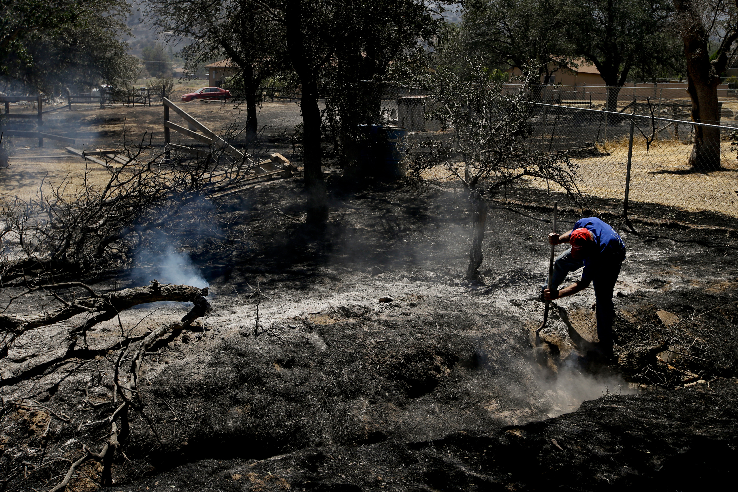 Alan Germain puts out hotspots on his neighbor's property destroyed by a wildfire near Lake Isabella, Calif., on June 24, 2016. (Jae C. Hong—AP)