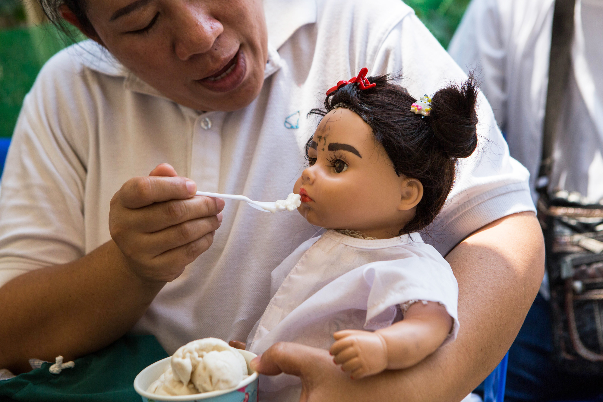 A woman named Pita feeds her Luk Thep doll Natalie coconut ice cream on March 21, 2016.
