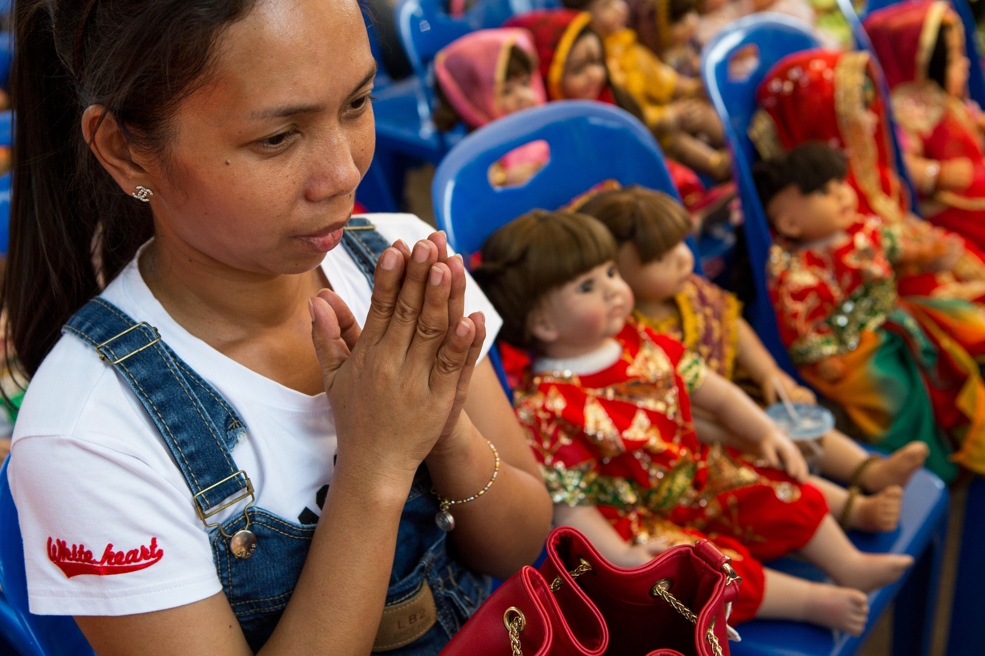A woman surrounded by Luk Thep dolls prays on March 21, 2016.