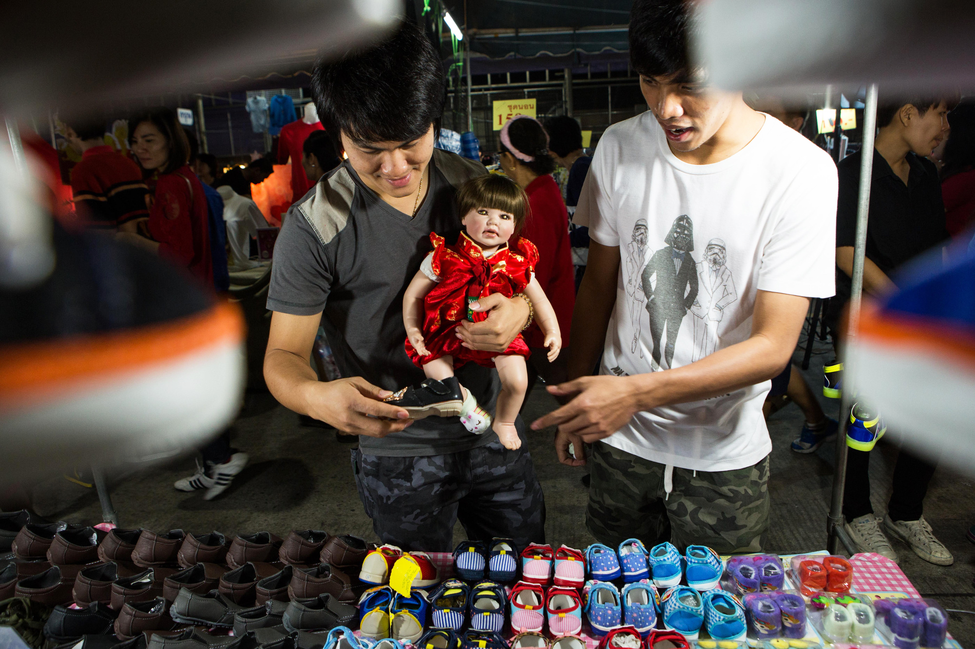 A couple shops for shoes for their Luk Thep doll at an outdoor market in Nakhon Sawan, Thailand on Feb. 10, 2016 .