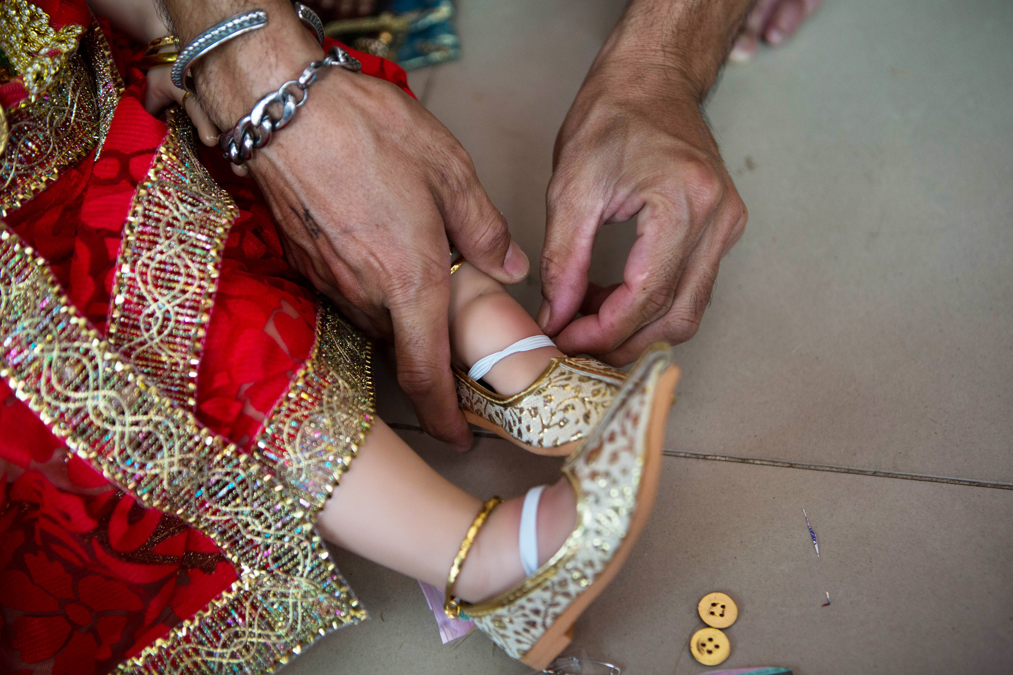 Handmade shoes are placed on a Luk Thep doll's feet in preparation for an event on March 17, 2016.