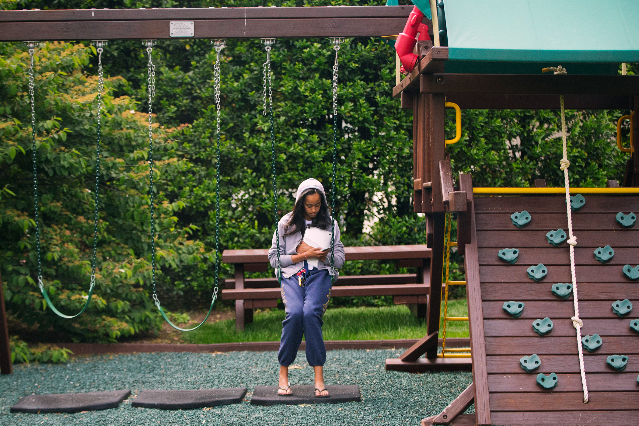 MMay 18, 2016 Malia Obama uses her phone at the swing and play set on the south grounds of the White House outside of the Oval Office in Washington.