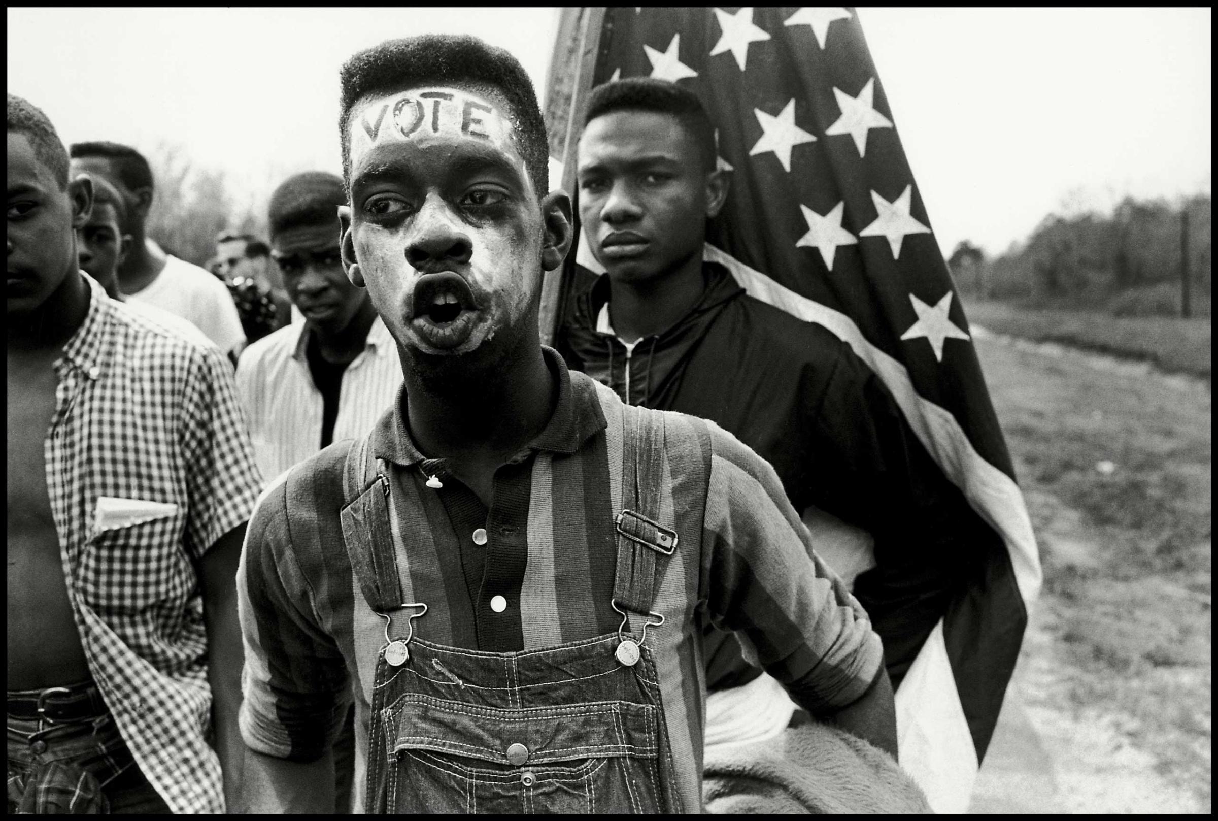 USA. Alabama. 1965. Led by Martin Luther King Jr., a group of civil rights demonstrators march from Selma to Montgomery to fight for black suffrage. A young African American man with the word "VOTE" on his forehead.