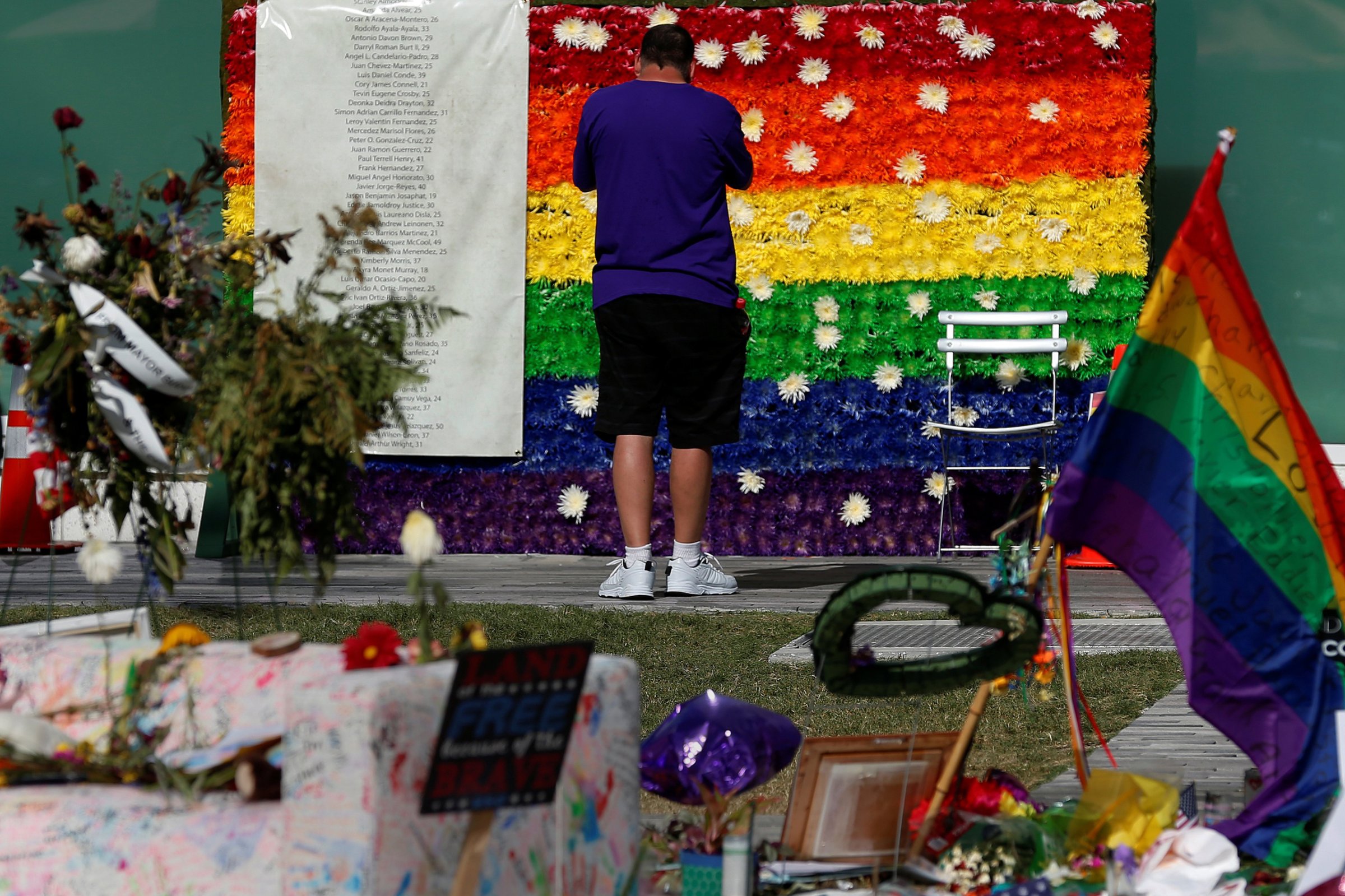 A man pays respect at a rainbow flower wall as part of the makeshift memorial for the Pulse nightclub mass shooting victims last week in Orlando, on June 21, 2016.